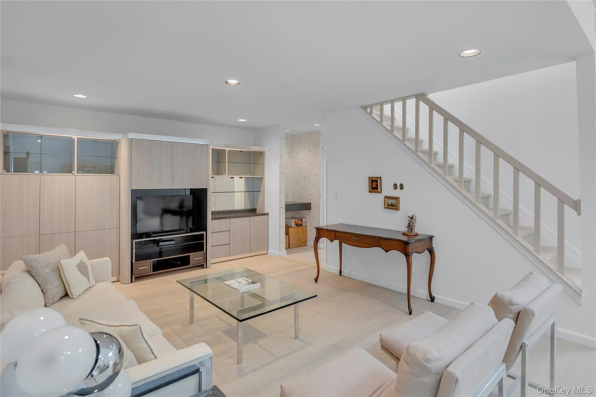 Recessed lighting illuminates this living space featuring a light wood-finish built-in cabinetry, mi Recessed lighting illuminates this living space featuring a light wood-finish built-in cabinetry, mi