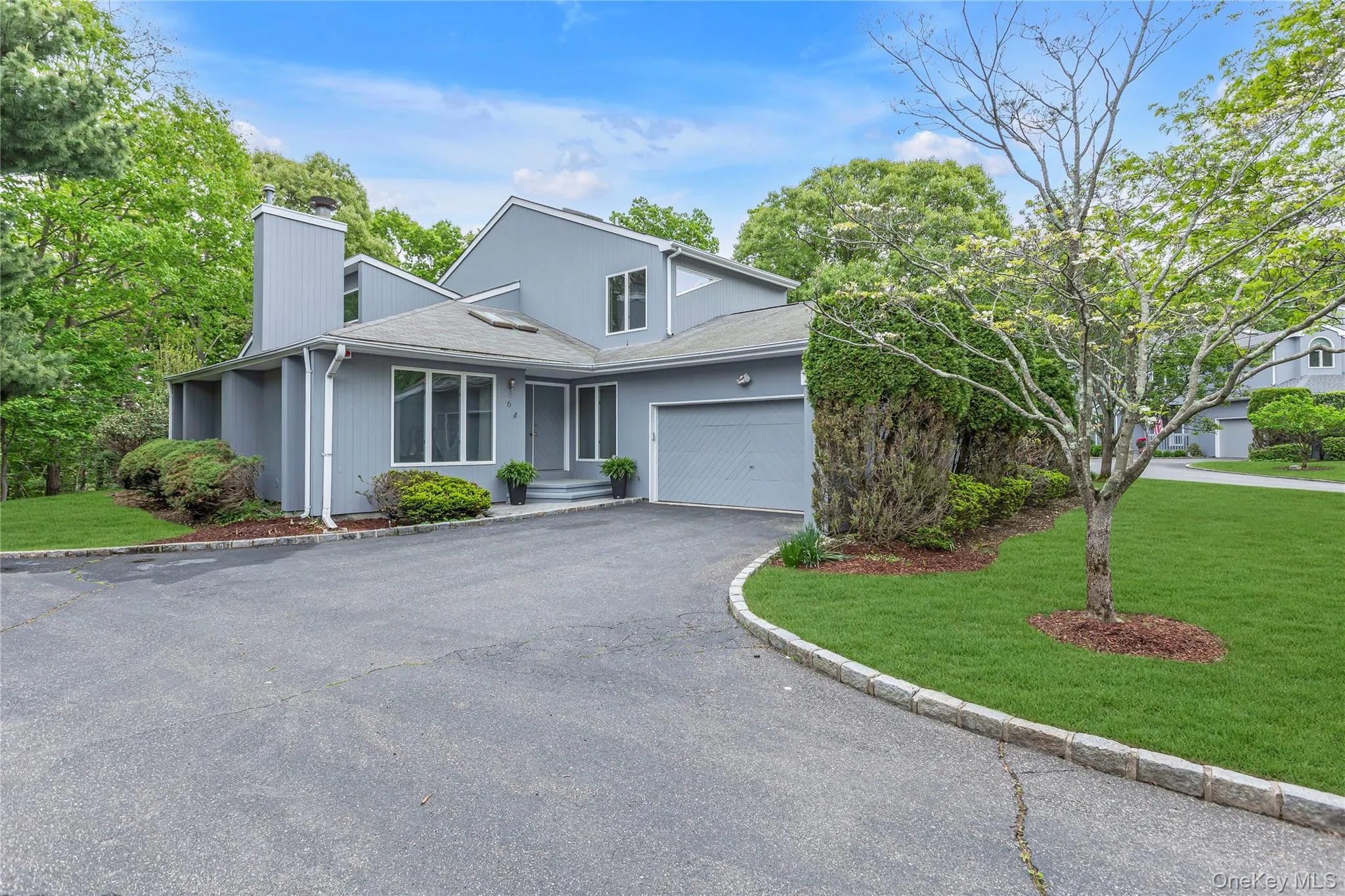 Contemporary exterior with an attached garage, a paved driveway, and manicured landscaping. Contemporary exterior with an attached garage, a paved driveway, and manicured landscaping.