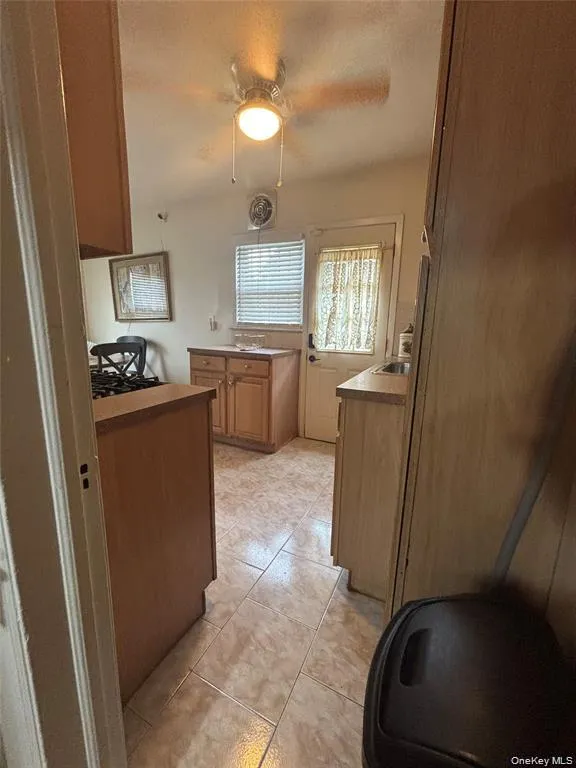 Tiled flooring, wood-finish cabinetry, and a ceiling fan with integrated lighting Tiled flooring, wood-finish cabinetry, and a ceiling fan with integrated lighting