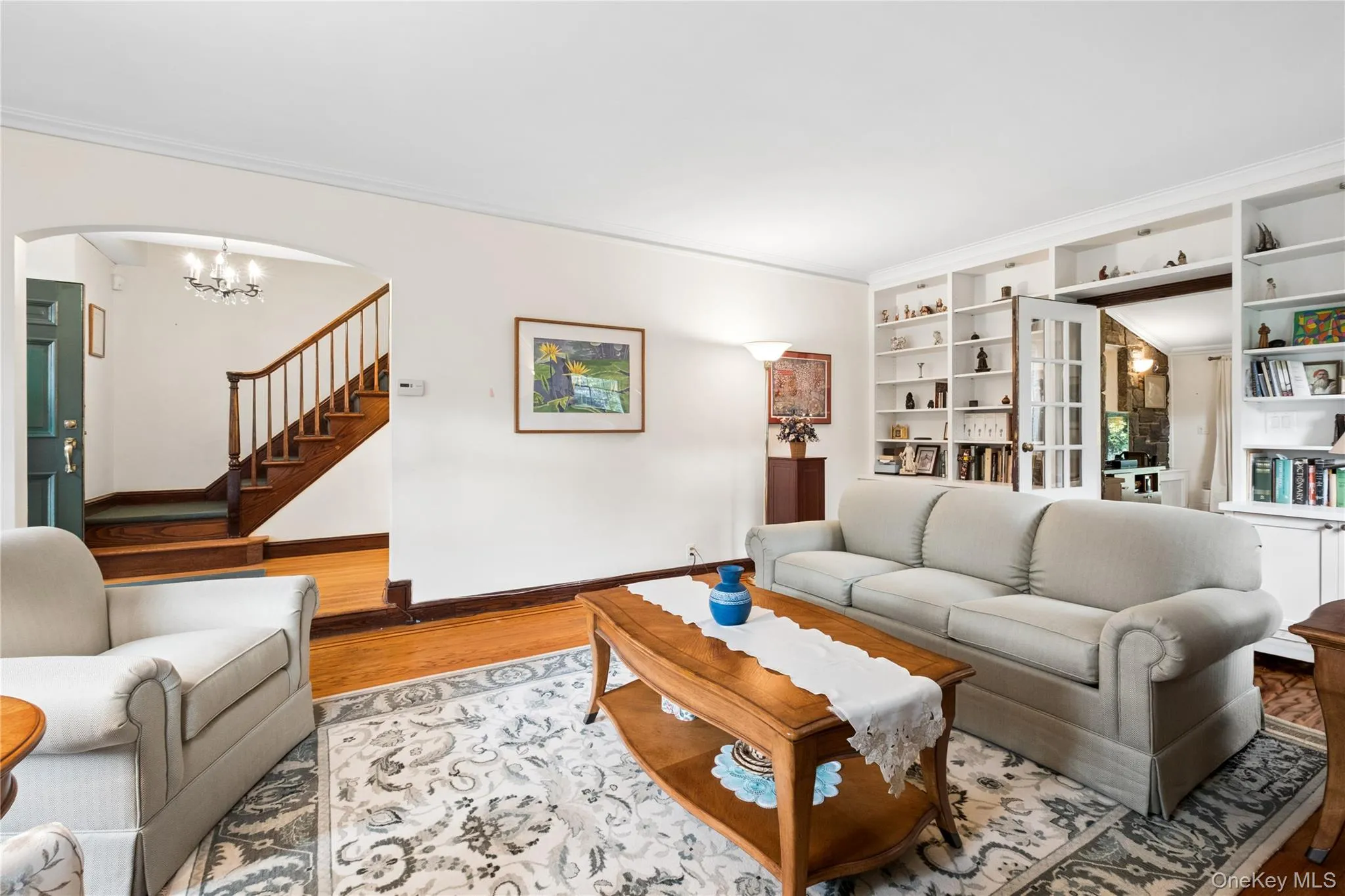Living Room with built-in shelves and storage cabinets and view of entrance foyer Living Room with built-in shelves and storage cabinets and view of entrance foyer