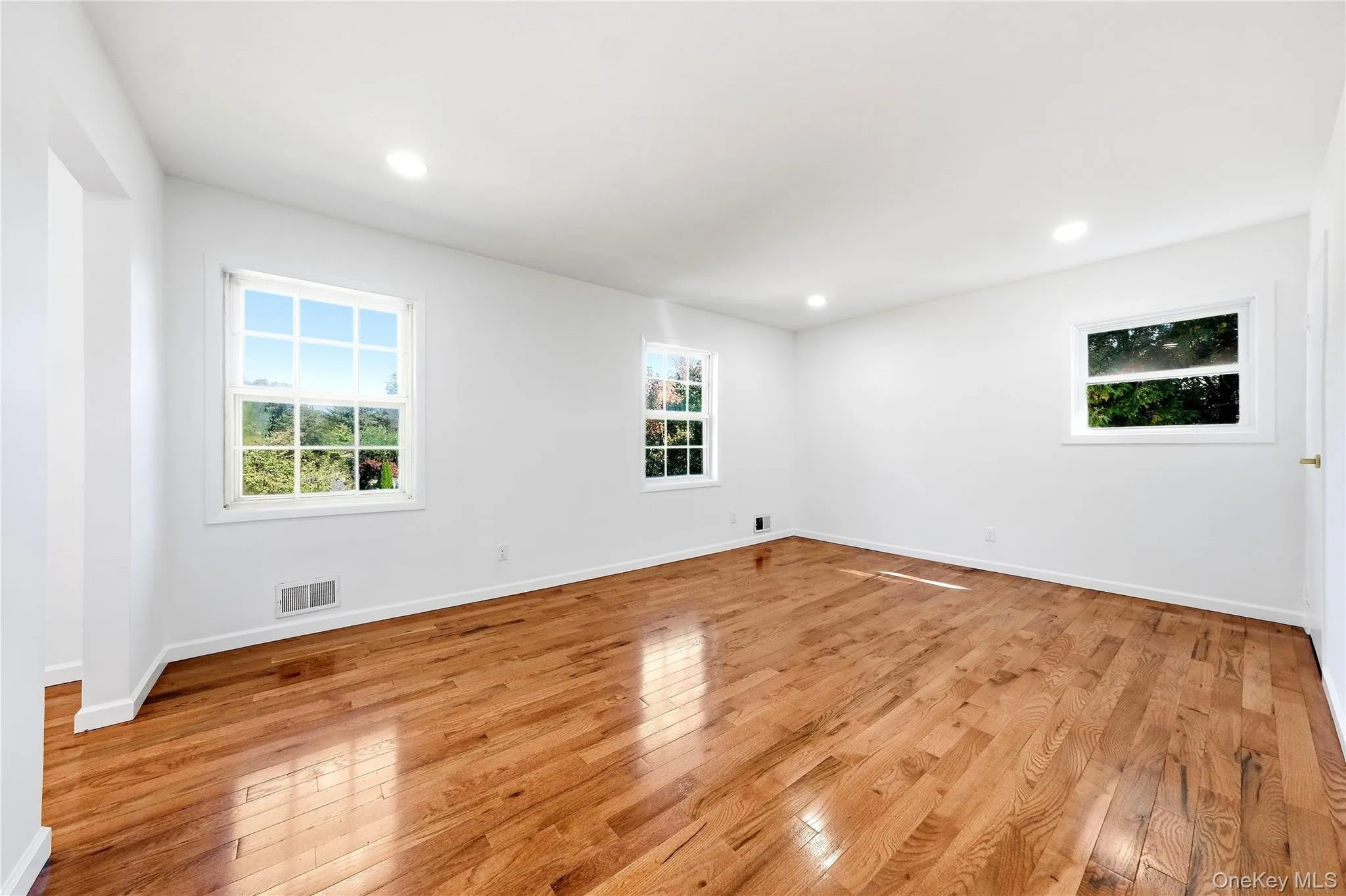 Hardwood flooring, recessed lighting, white walls, and multiple windows Hardwood flooring, recessed lighting, white walls, and multiple windows