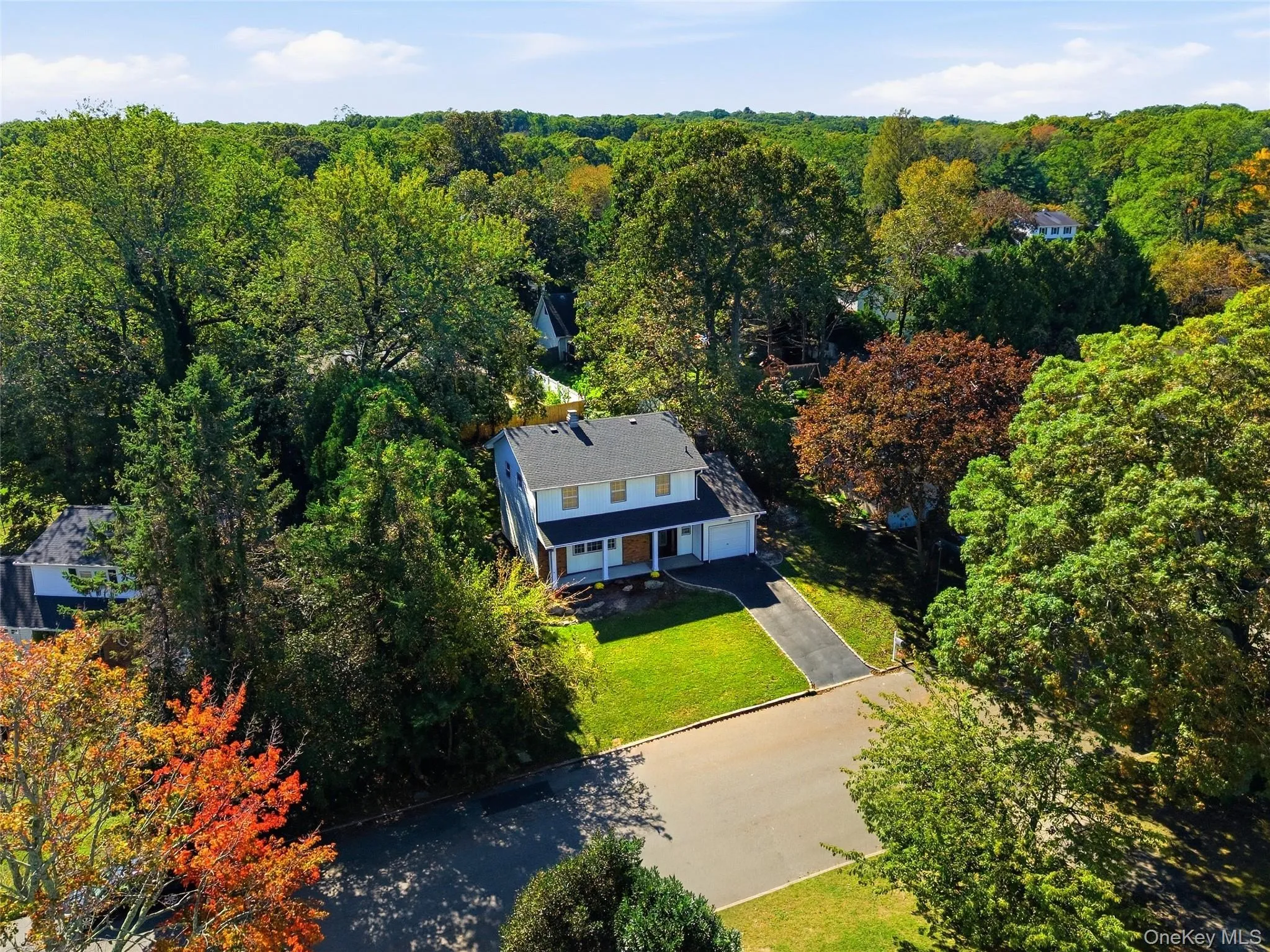 Two-story residence with a dark shingle roof, light-colored siding, and a paved driveway Two-story residence with a dark shingle roof, light-colored siding, and a paved driveway