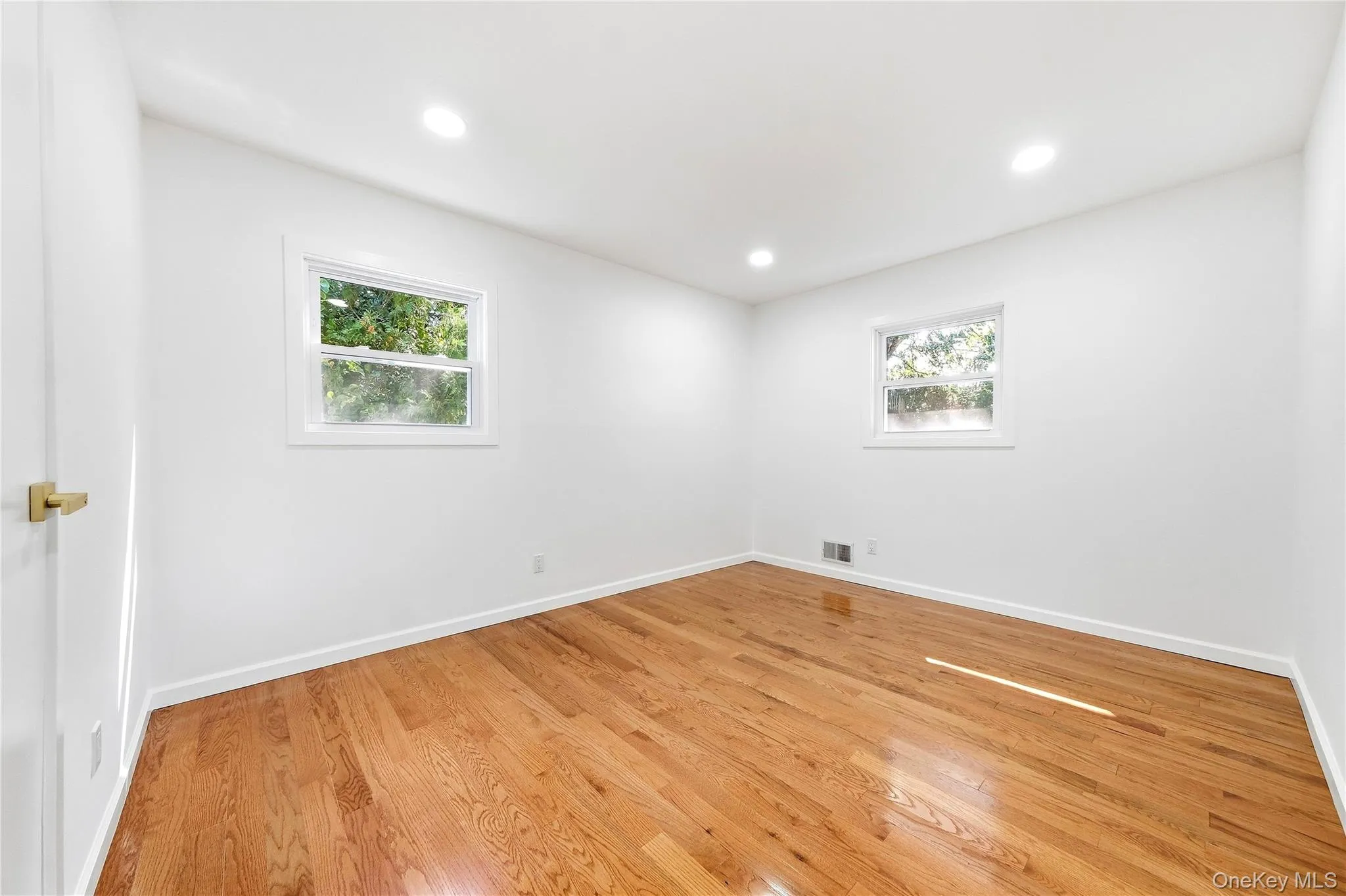 Hardwood flooring, recessed lighting, white walls, and two windows with white trim Hardwood flooring, recessed lighting, white walls, and two windows with white trim