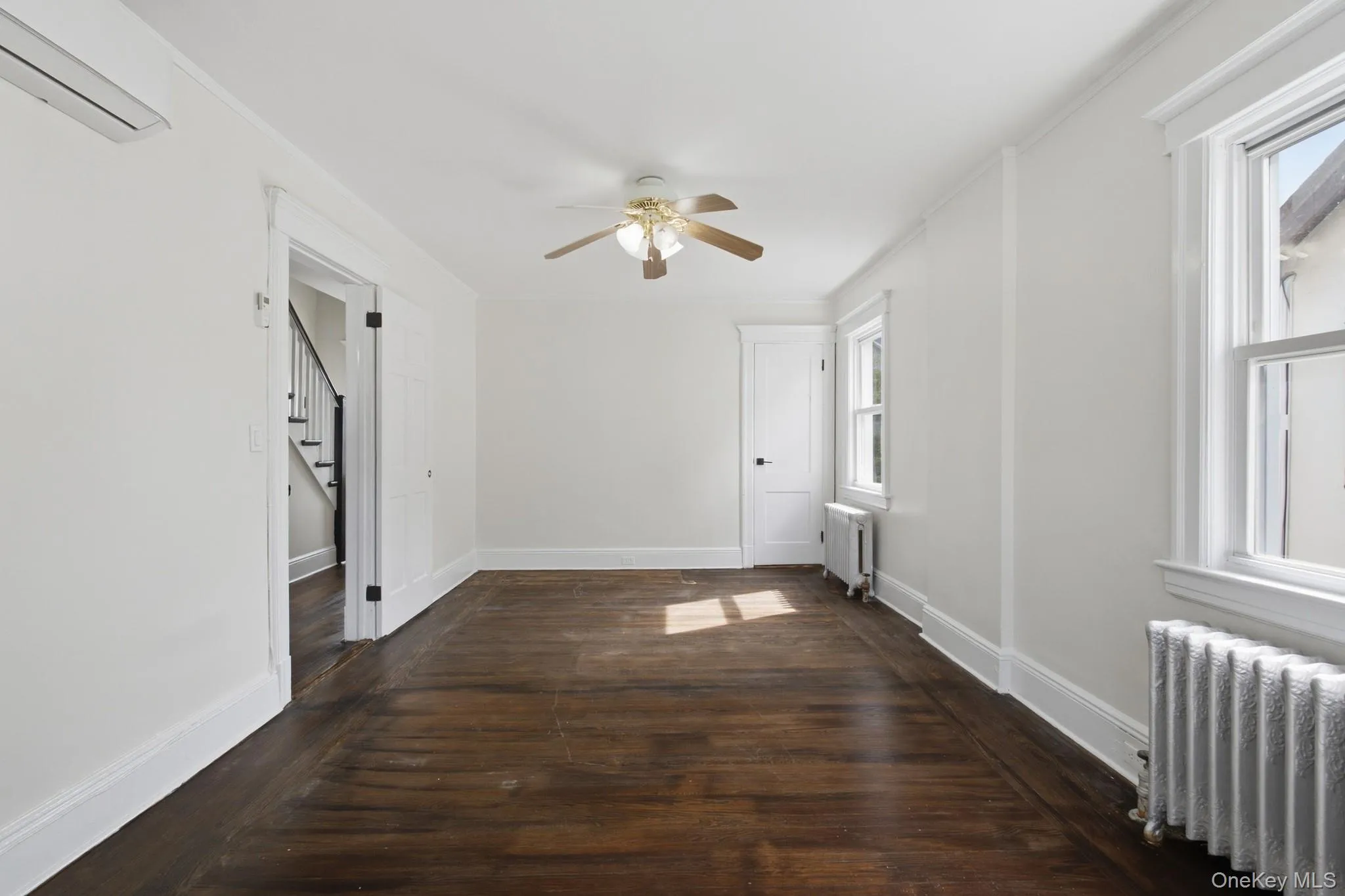 Hardwood-finish flooring, white painted walls, ceiling fan, white trim, and a split AC unit Hardwood-finish flooring, white painted walls, ceiling fan, white trim, and a split AC unit