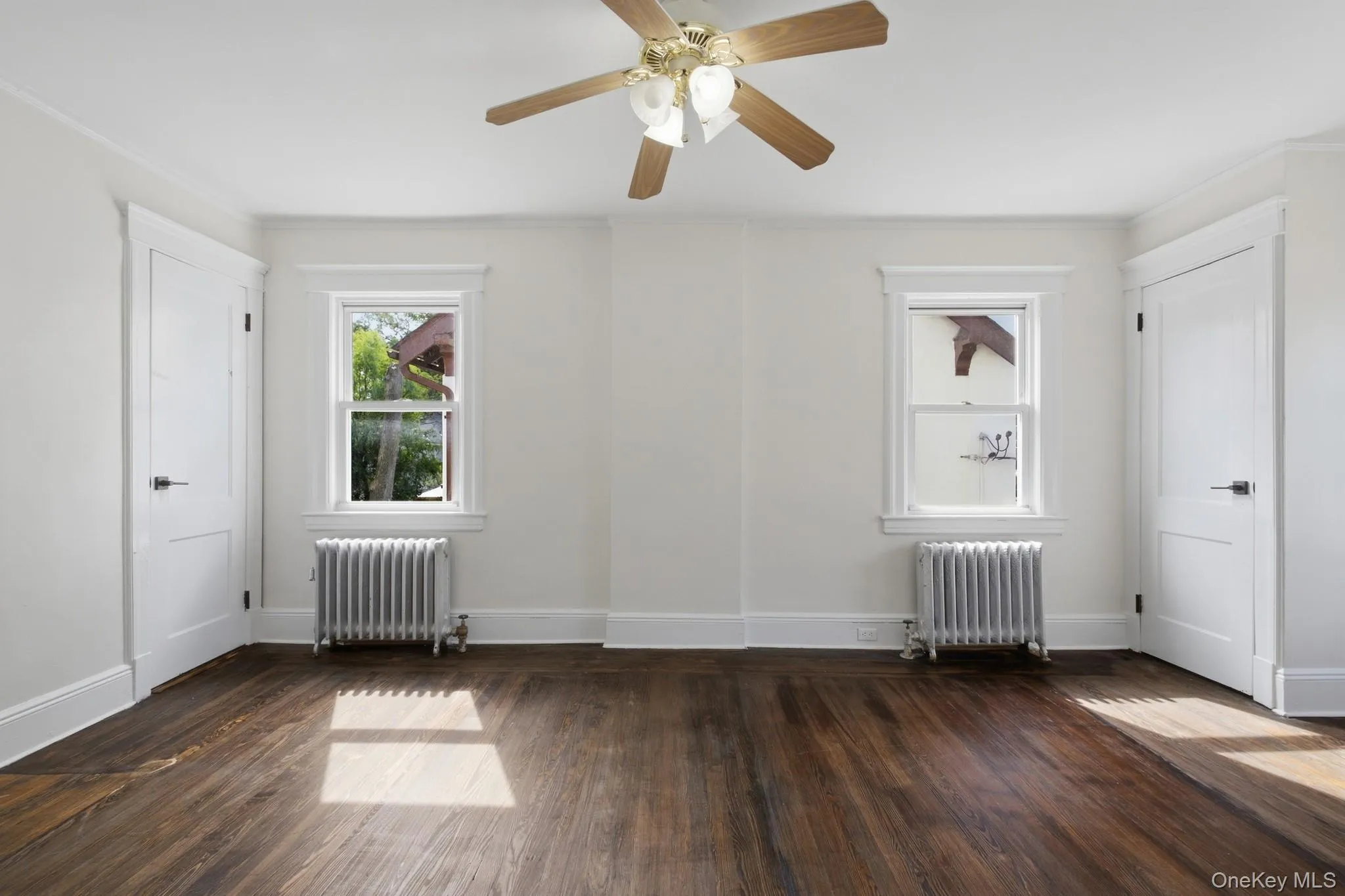 Hardwood flooring, painted walls, two windows, two doors, and a ceiling fan with integrated lighting Hardwood flooring, painted walls, two windows, two doors, and a ceiling fan with integrated lighting