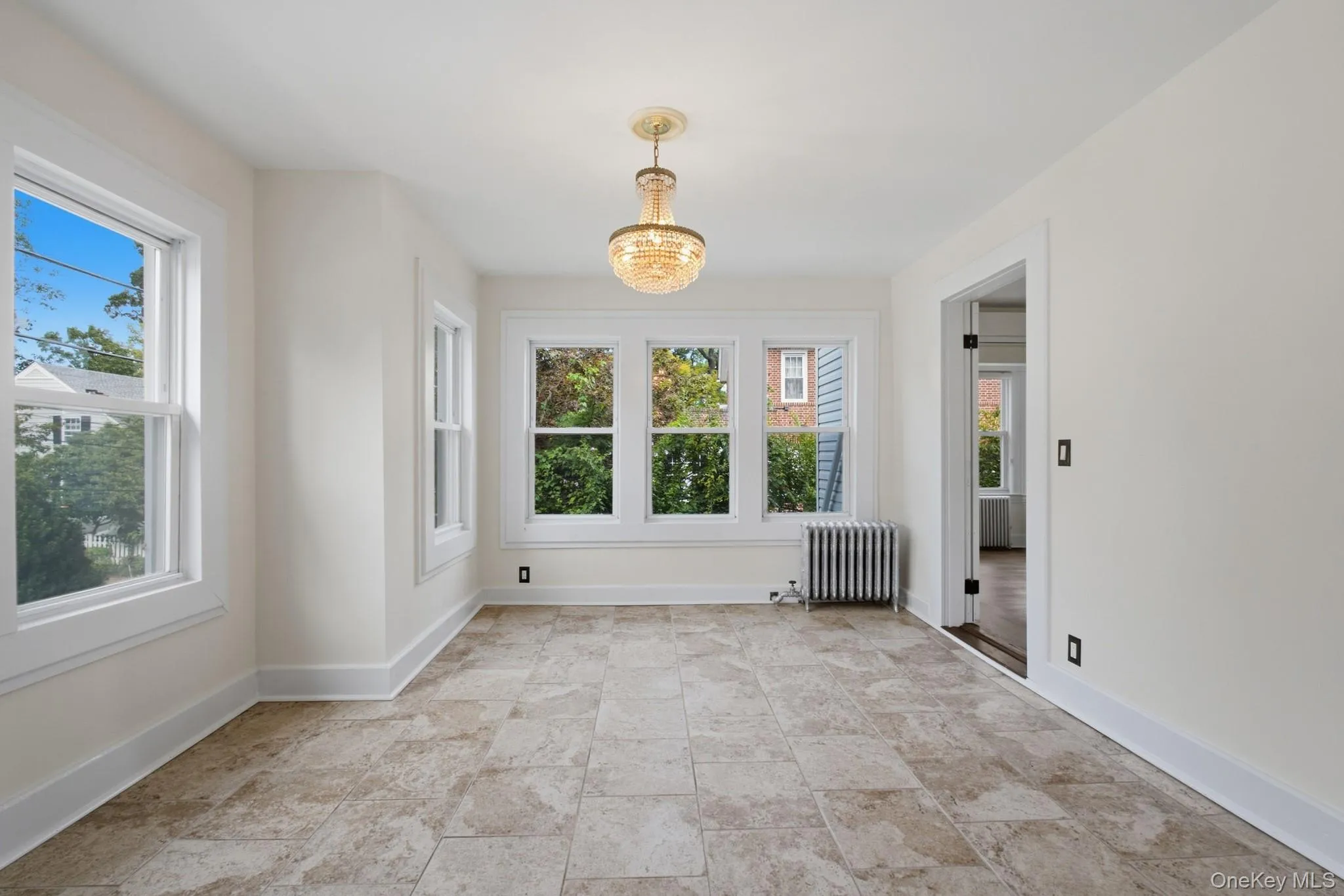 Tile flooring, multiple windows, a decorative chandelier, and a radiator Tile flooring, multiple windows, a decorative chandelier, and a radiator