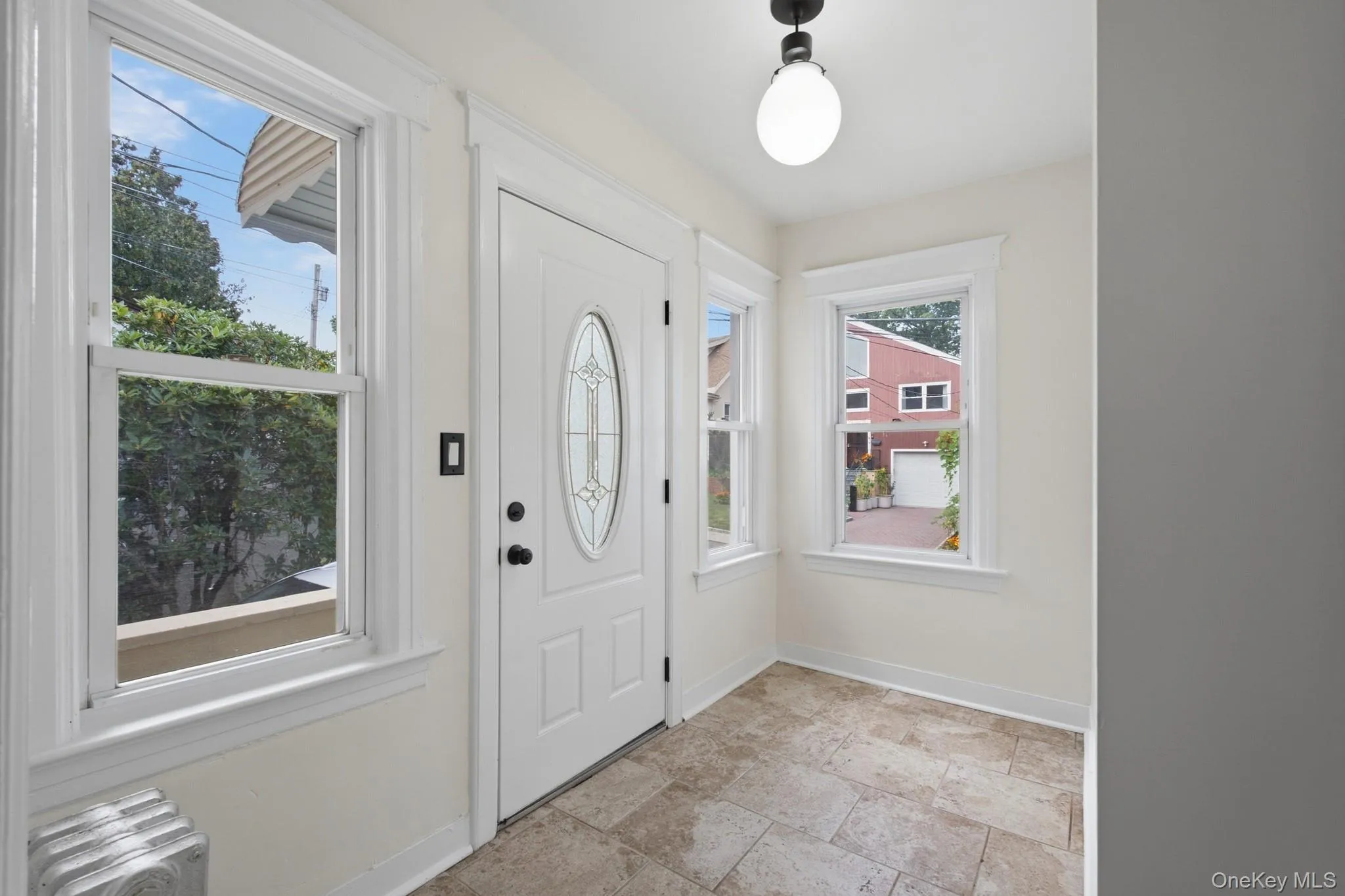 Entryway featuring a white door with an oval glass insert, multiple windows with white trim, and tiled flooring Entryway featuring a white door with an oval glass insert, multiple windows with white trim, and tiled flooring