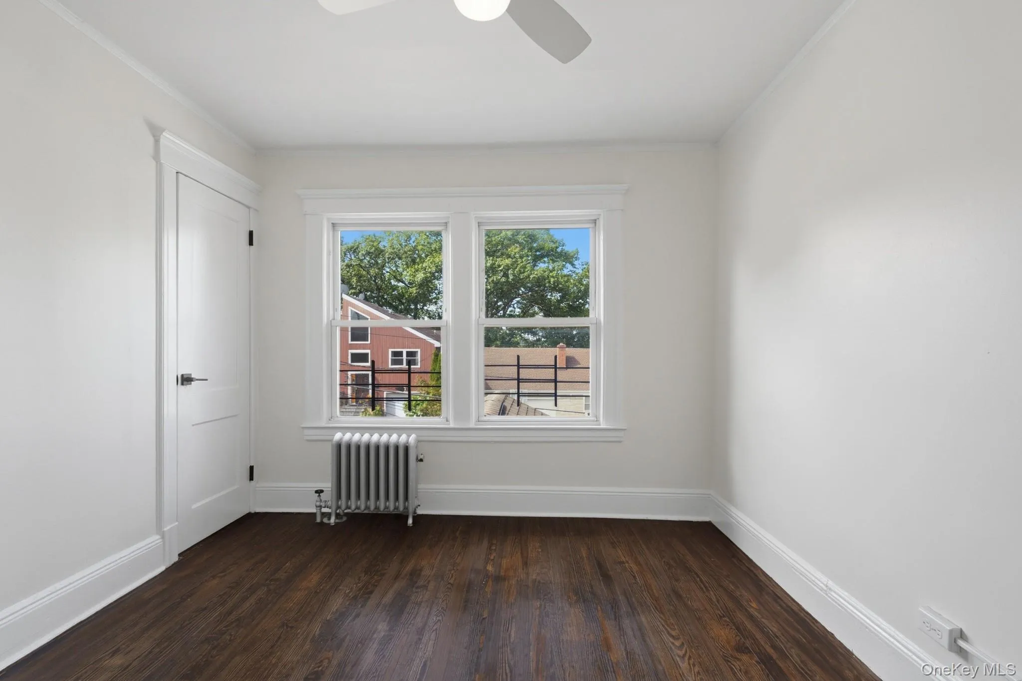 Dark wood-finish flooring, white trim, white door, and a ceiling fan Dark wood-finish flooring, white trim, white door, and a ceiling fan