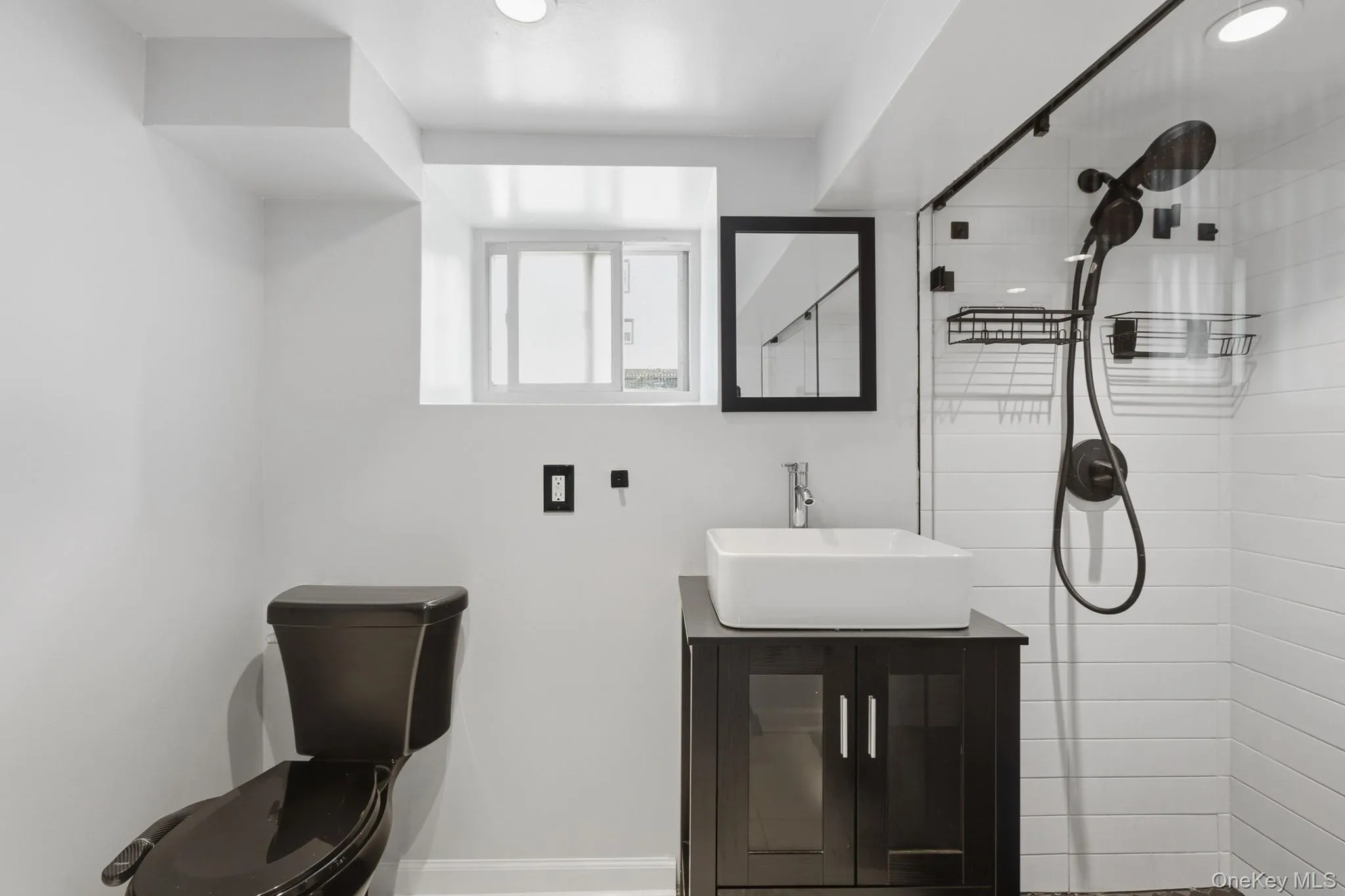Walk-in shower with a glass enclosure, white subway tile, and a black shower fixture Walk-in shower with a glass enclosure, white subway tile, and a black shower fixture