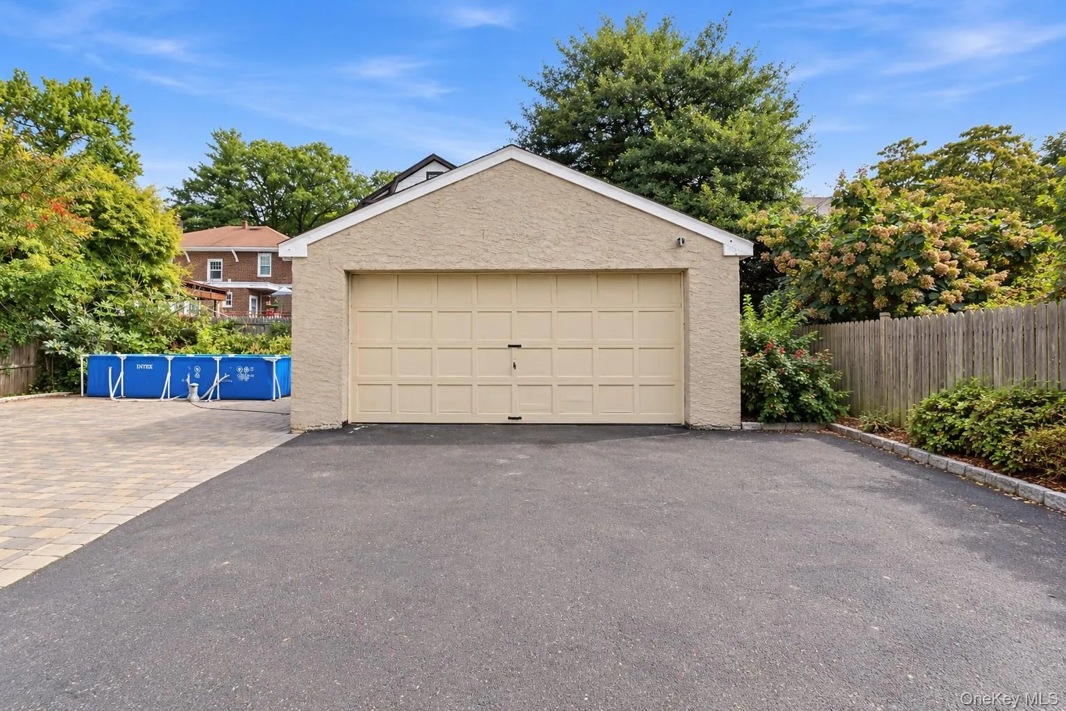Detached garage with stucco exterior and a paved driveway Detached garage with stucco exterior and a paved driveway