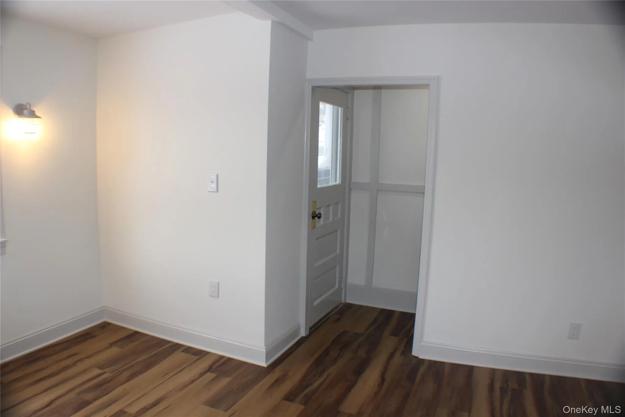 Spare room featuring baseboards and dark wood-style flooring Spare room featuring baseboards and dark wood-style flooring