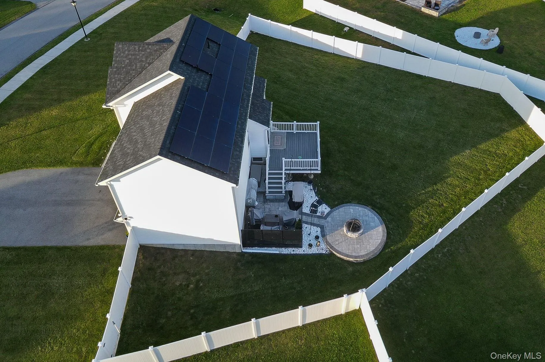 White exterior with a dark shingle roof, solar panel array, and a composite deck White exterior with a dark shingle roof, solar panel array, and a composite deck