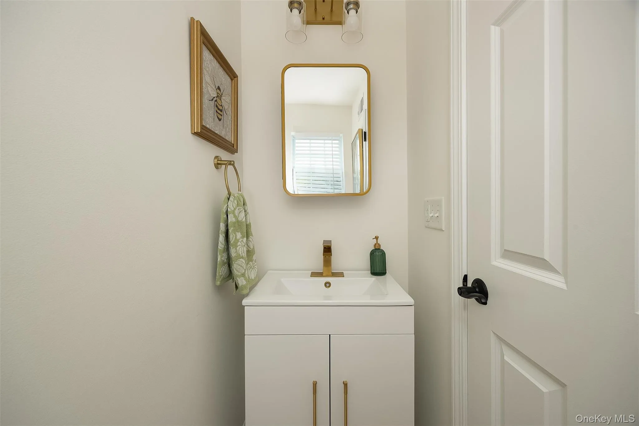 White vanity with gold-tone hardware, gold-tone faucet, and rectangular undermount sink in first floor bath White vanity with gold-tone hardware, gold-tone faucet, and rectangular undermount sink in first floor bath