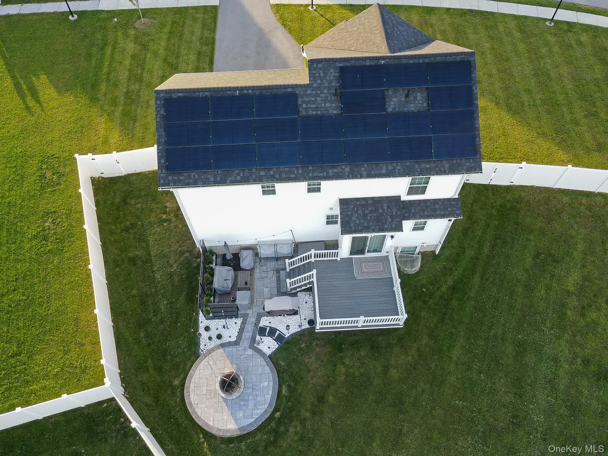 Rooftop solar panel array, composite deck, paver patio, integrated fire pit, and white vinyl perimeter fencing Rooftop solar panel array, composite deck, paver patio, integrated fire pit, and white vinyl perimeter fencing
