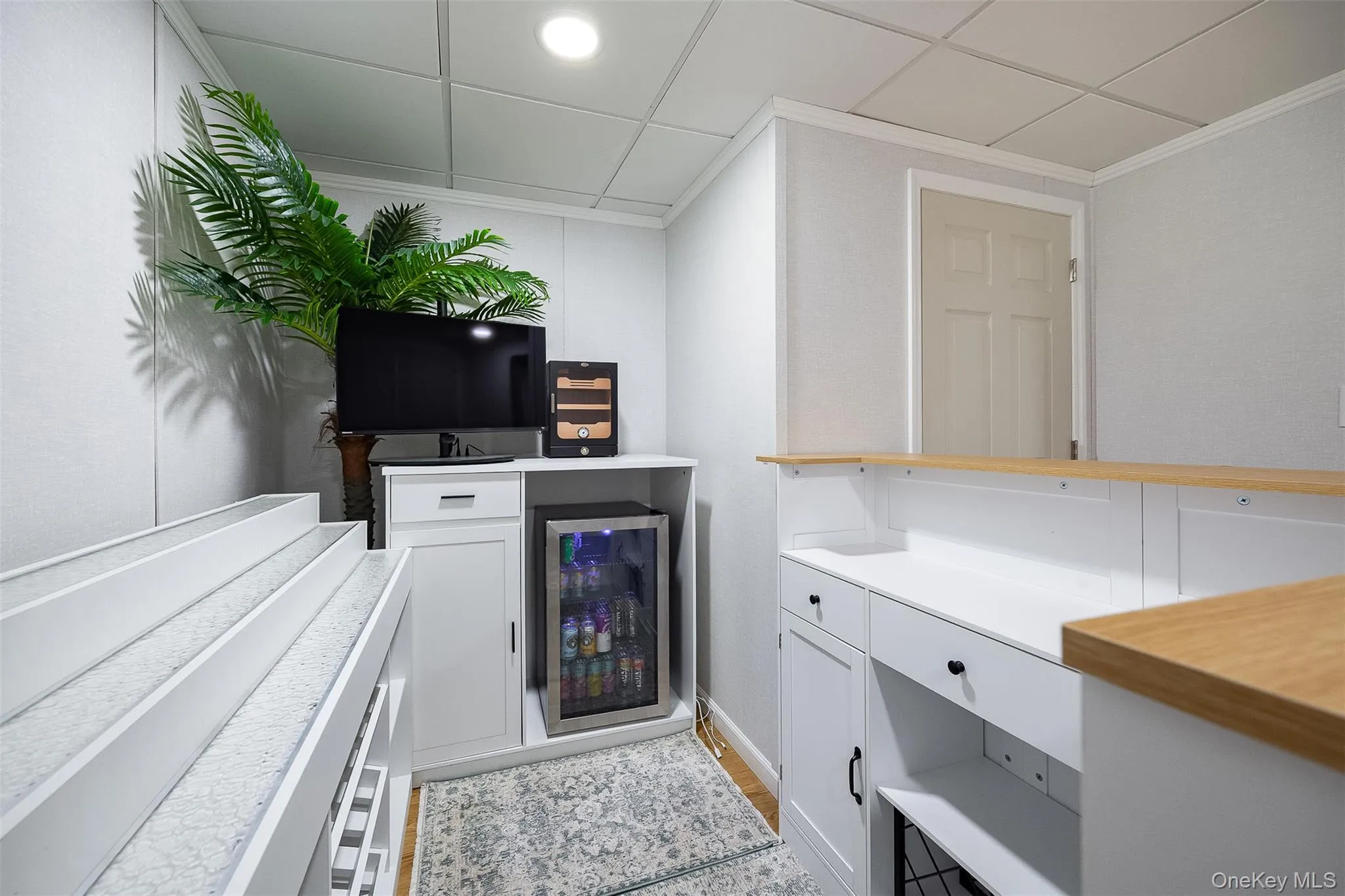 Built-in bar area featuring white cabinetry, light wood-finish countertops, and an integrated beverage refrigerator Built-in bar area featuring white cabinetry, light wood-finish countertops, and an integrated beverage refrigerator
