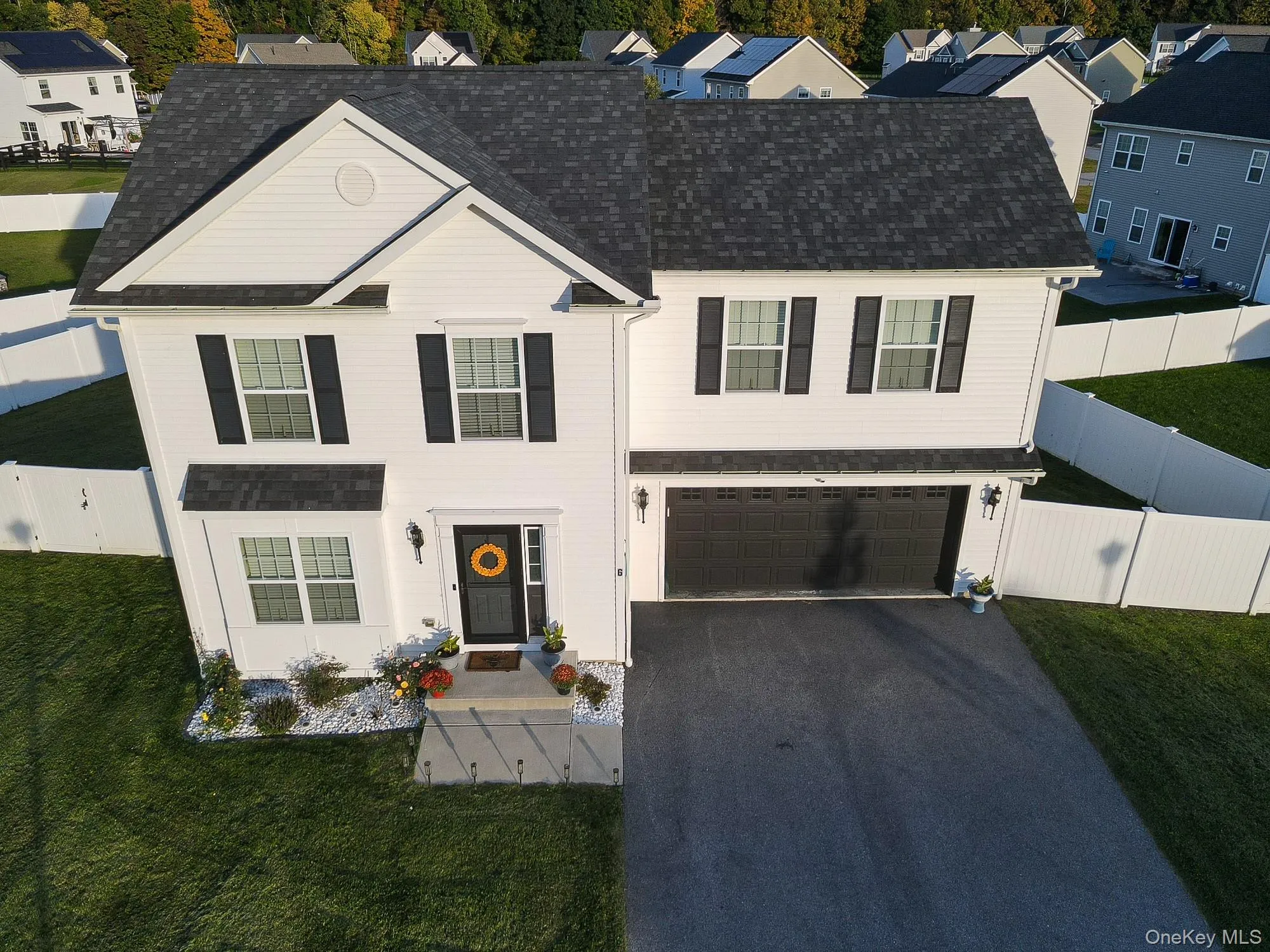 White siding with black shutters, dark shingle roof, two-car garage, paved driveway, and a white picket fence White siding with black shutters, dark shingle roof, two-car garage, paved driveway, and a white picket fence