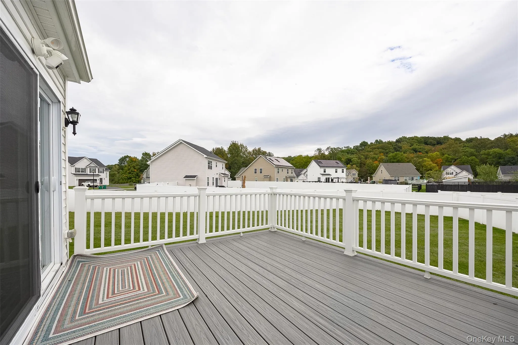 Spacious deck with gray composite decking, white railing, and sliding glass door Spacious deck with gray composite decking, white railing, and sliding glass door