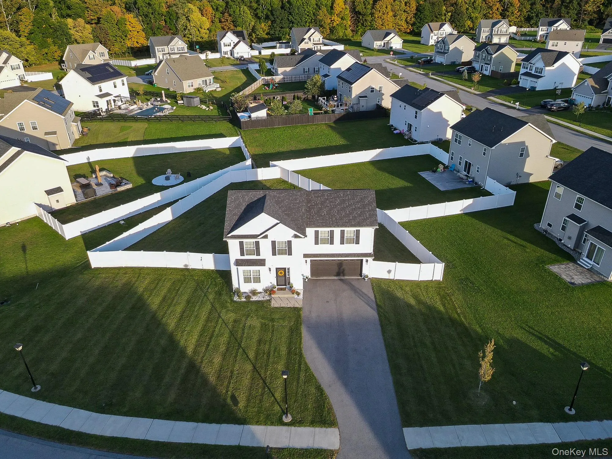 Two-story residence with a dark gray roof, a two-car garage, and a paved driveway Two-story residence with a dark gray roof, a two-car garage, and a paved driveway