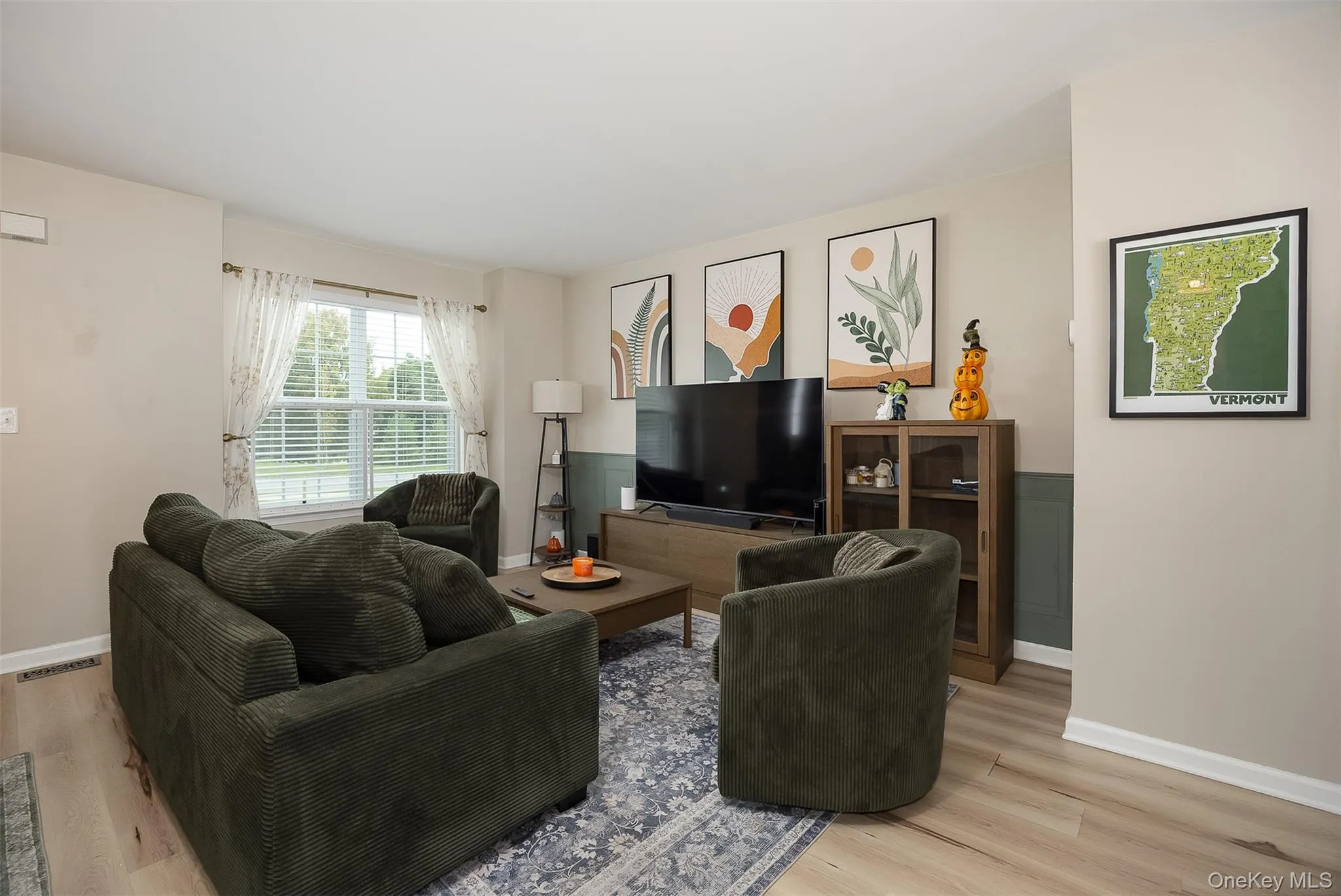 Light vinyl plank flooring, two-tone wall treatment, and a large window with blinds Light vinyl plank flooring, two-tone wall treatment, and a large window with blinds