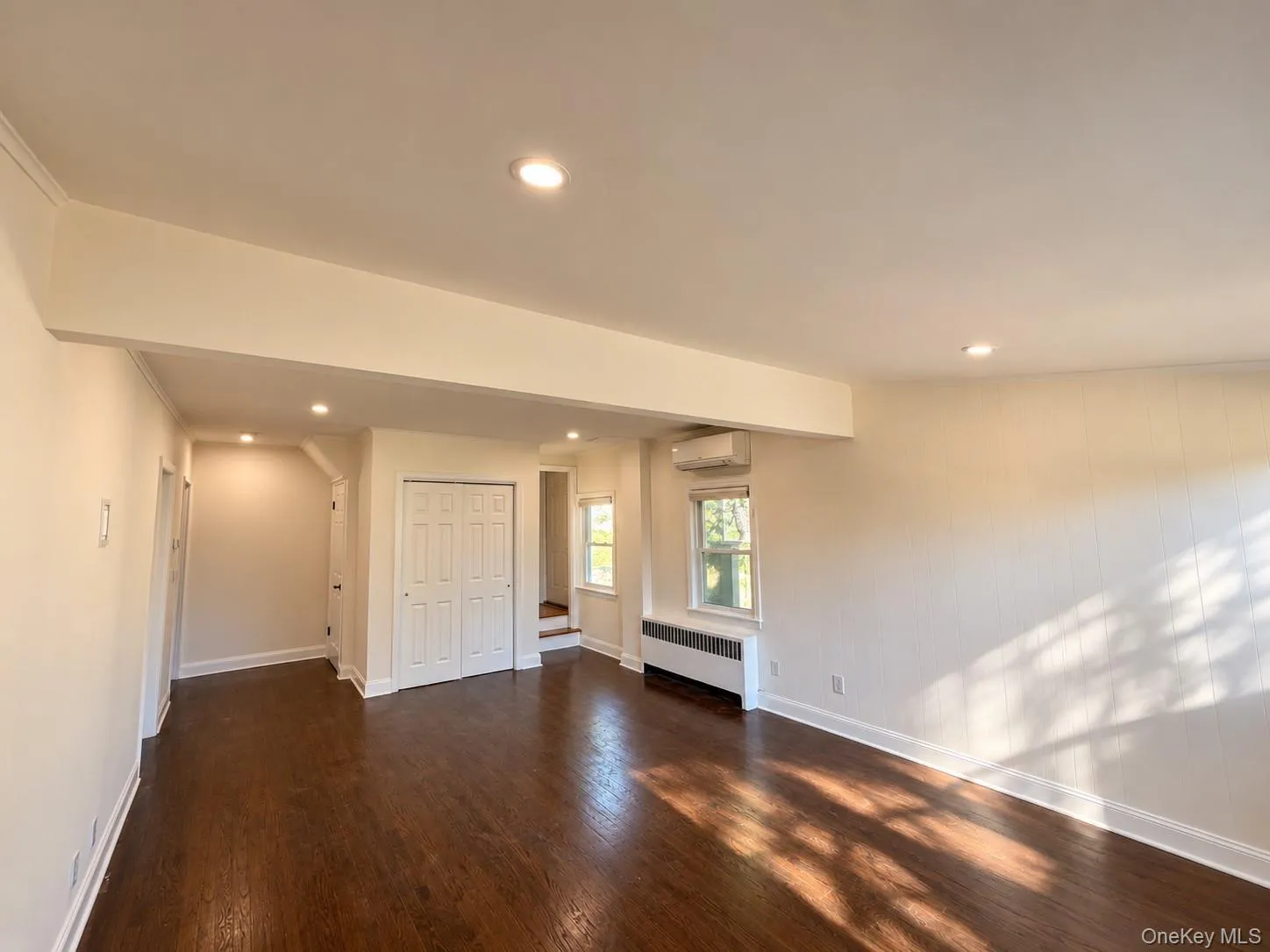 Hardwood flooring, recessed lighting, air conditioning unit, and white bi-fold closet doors Hardwood flooring, recessed lighting, air conditioning unit, and white bi-fold closet doors