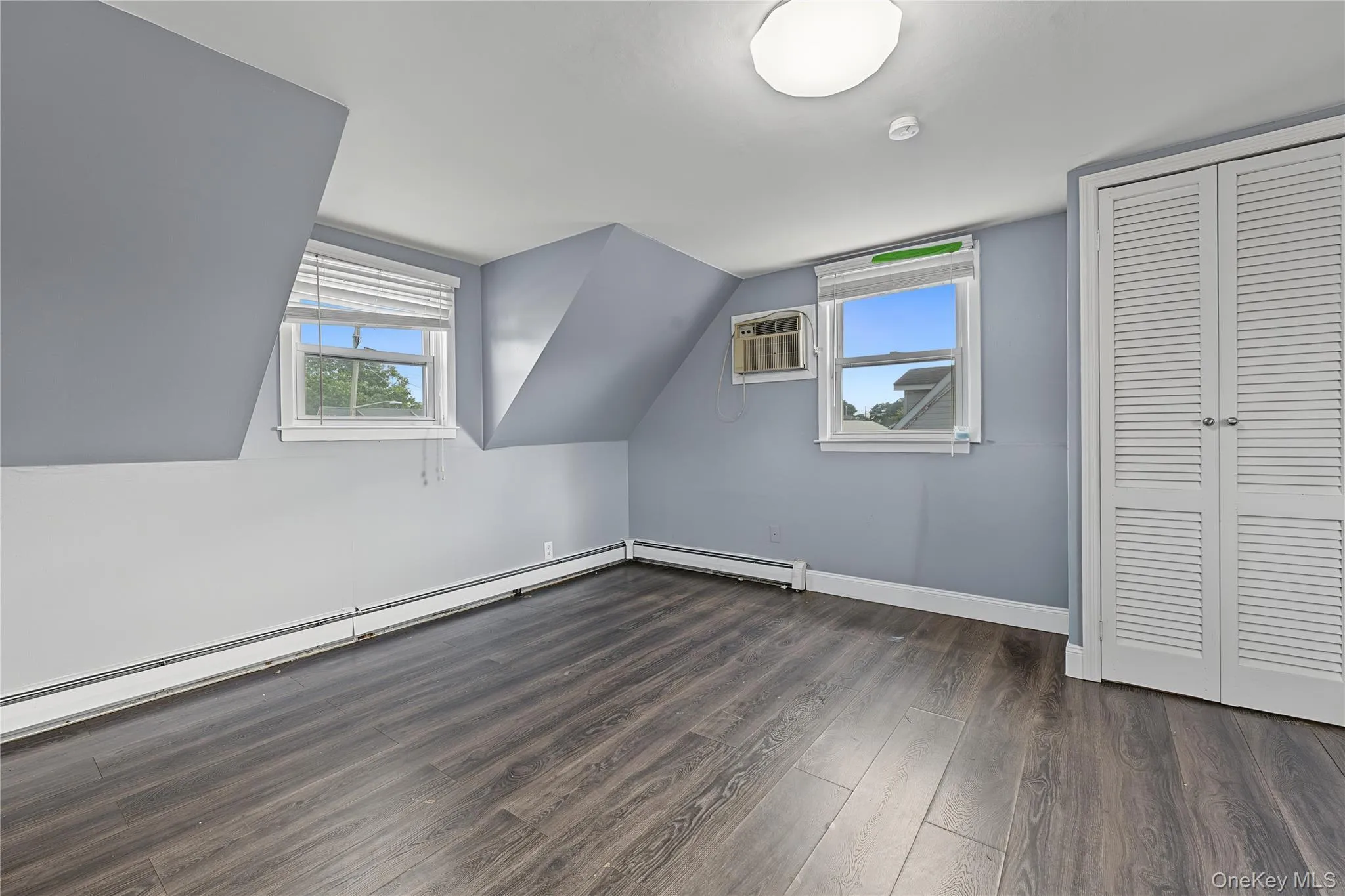 Fourth bedroom located on the second floor has two windows, bi-fold closet doors, and wall-mounted air conditioner Fourth bedroom located on the second floor has two windows, bi-fold closet doors, and wall-mounted air conditioner