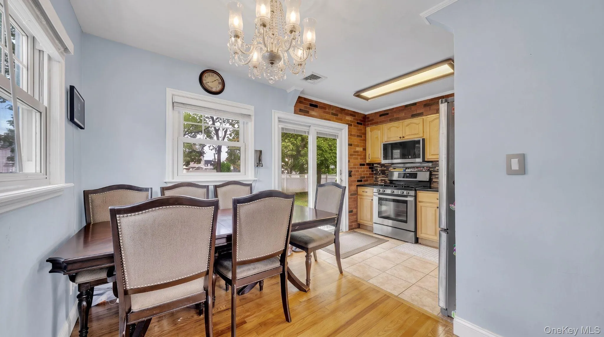 Wood-finish flooring, multiple windows, kitchen with stainless steel appliances, brick-finish kitchen wall, sliding glass patio door Wood-finish flooring, multiple windows, kitchen with stainless steel appliances, brick-finish kitchen wall, sliding glass patio door