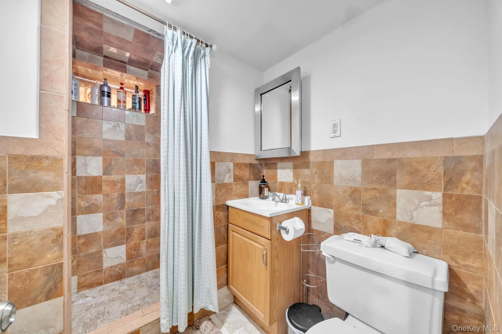 Tiled shower with an integrated niche, wood-finish vanity, and a framed mirror Tiled shower with an integrated niche, wood-finish vanity, and a framed mirror