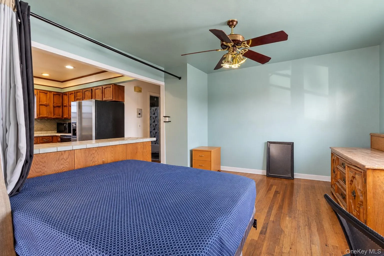 Wood-finish flooring, ceiling fan with integrated lighting, tiled breakfast bar, and kitchen cabinetry Wood-finish flooring, ceiling fan with integrated lighting, tiled breakfast bar, and kitchen cabinetry