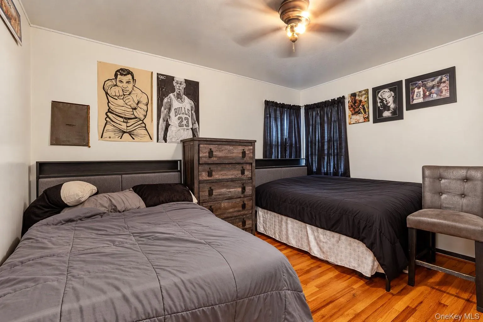 Interior room featuring wood-finish flooring, a ceiling fan with light fixture, and neutral wall coloring Interior room featuring wood-finish flooring, a ceiling fan with light fixture, and neutral wall coloring