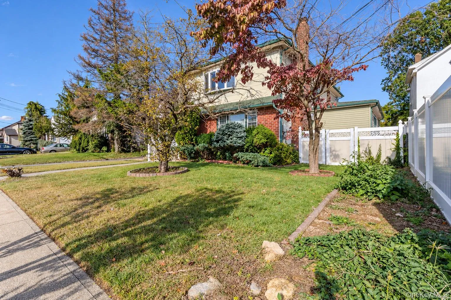 Two-story residence featuring a brick and siding exterior, a chimney, and a white privacy fence Two-story residence featuring a brick and siding exterior, a chimney, and a white privacy fence