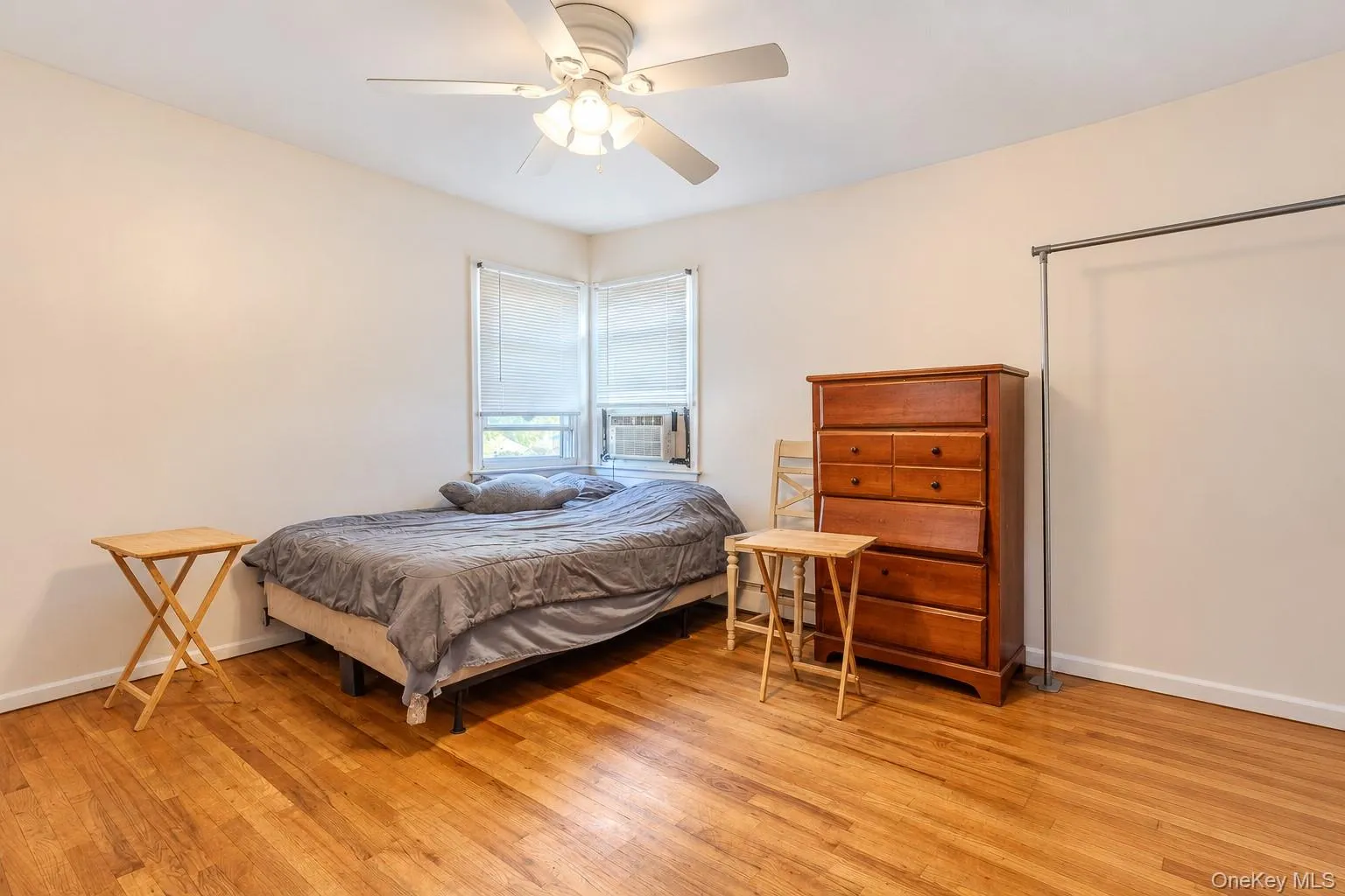 Wood-finish flooring, corner windows, and a ceiling-mounted fan with integrated light fixture Wood-finish flooring, corner windows, and a ceiling-mounted fan with integrated light fixture