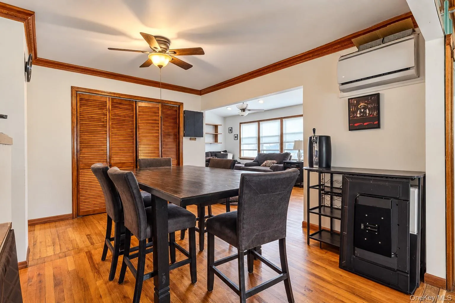 Wood-finish flooring, crown molding, louvered-panel closet doors, and a wall-mounted ductless air conditioning unit Wood-finish flooring, crown molding, louvered-panel closet doors, and a wall-mounted ductless air conditioning unit
