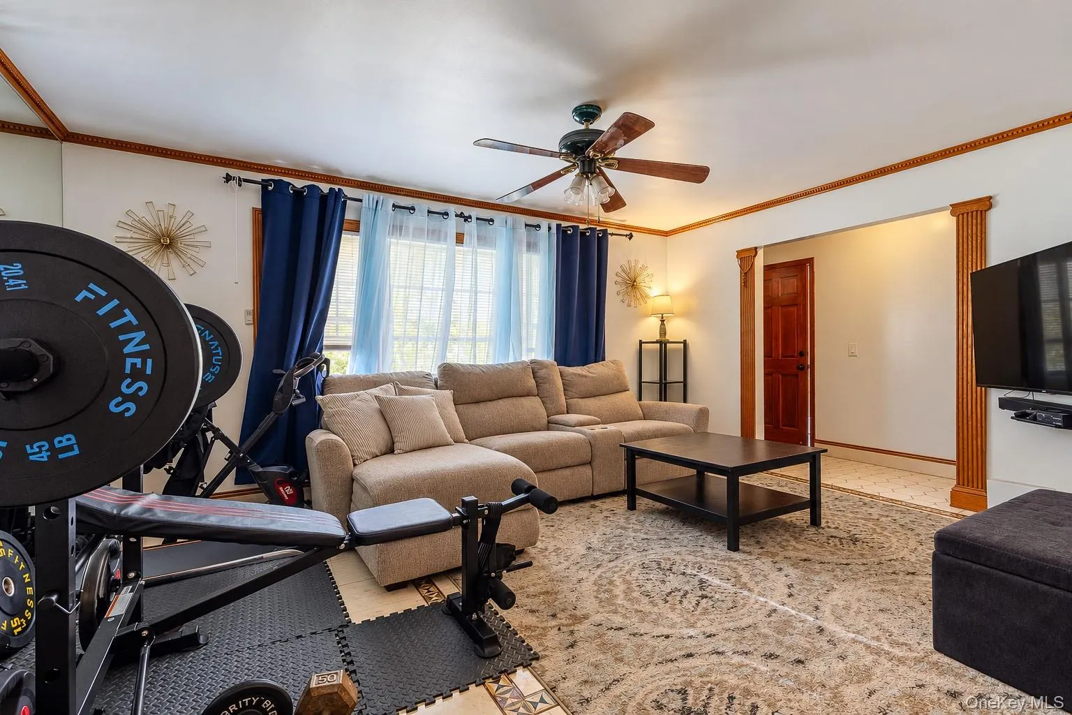 Multi-pane windows, wood-finish ceiling fan with integrated lighting, and decorative wood molding framing the entryway Multi-pane windows, wood-finish ceiling fan with integrated lighting, and decorative wood molding framing the entryway