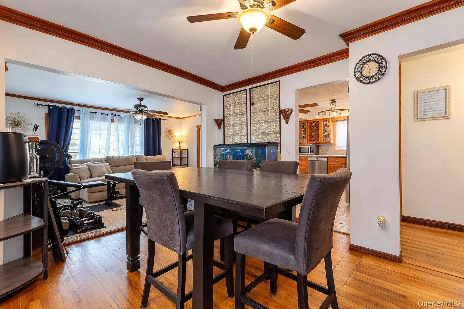 Dining area featuring wood-finish flooring, crown molding, and a central ceiling fan with integrated lighting Dining area featuring wood-finish flooring, crown molding, and a central ceiling fan with integrated lighting