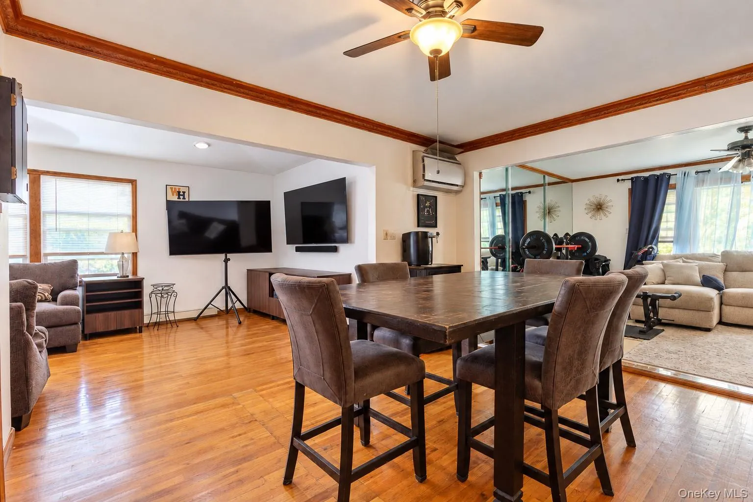 Wood-finish flooring, crown molding, ceiling fan with light fixture, mirrored wall accents, and recessed lighting Wood-finish flooring, crown molding, ceiling fan with light fixture, mirrored wall accents, and recessed lighting