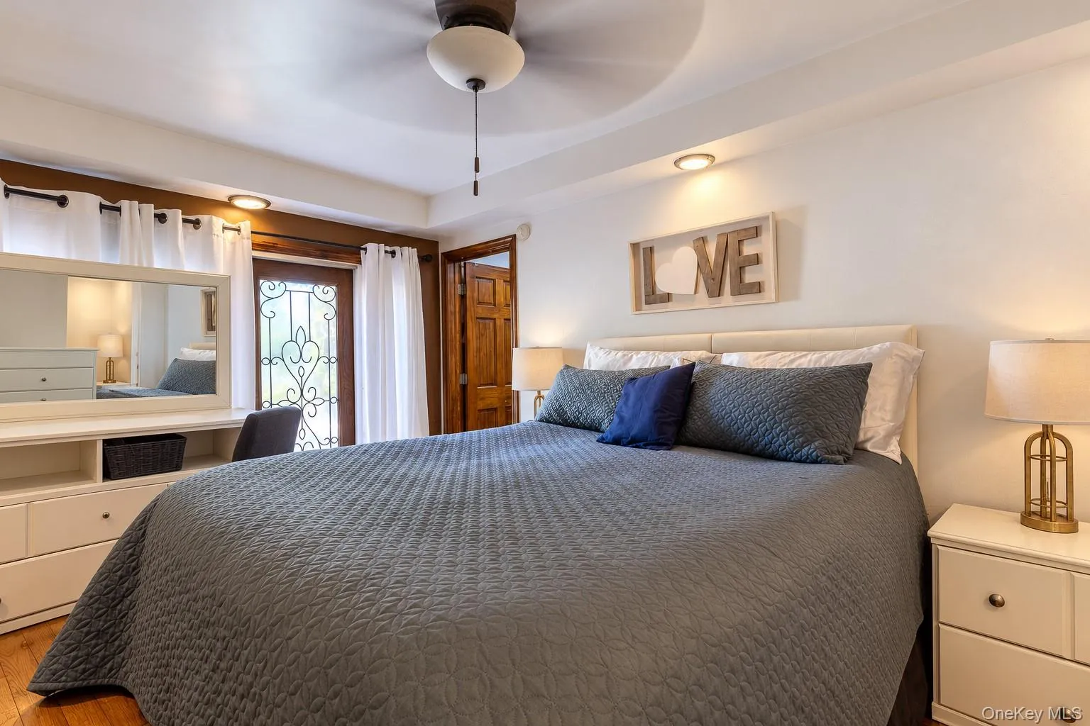 Tray ceiling with recessed lighting, ceiling fan, wood-finish flooring, built-in cabinetry, and decorative iron-detail exterior door Tray ceiling with recessed lighting, ceiling fan, wood-finish flooring, built-in cabinetry, and decorative iron-detail exterior door