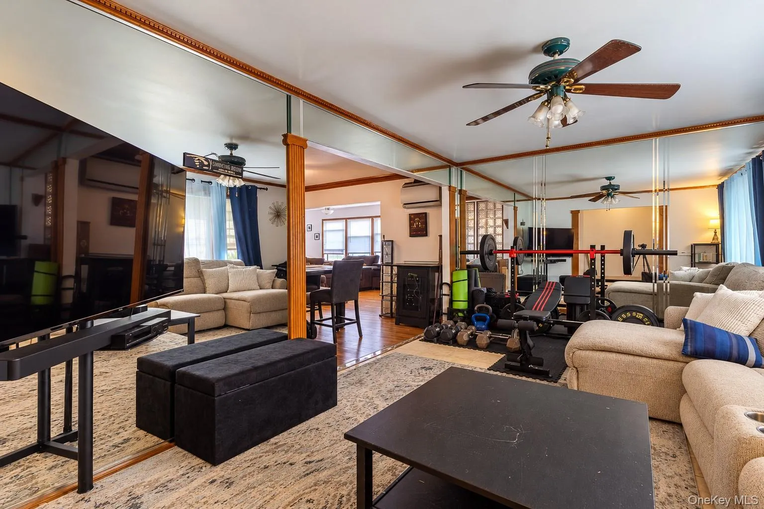 Interior space featuring full-wall mirrors, wood-trim accents, and a ceiling fan with integrated lighting Interior space featuring full-wall mirrors, wood-trim accents, and a ceiling fan with integrated lighting