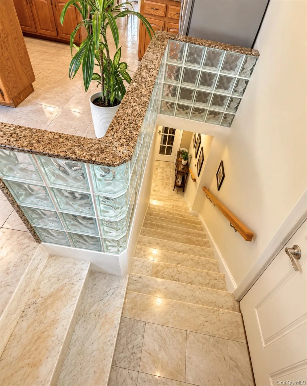 Staircase featuring light-toned tiled steps and a wood handrail Staircase featuring light-toned tiled steps and a wood handrail