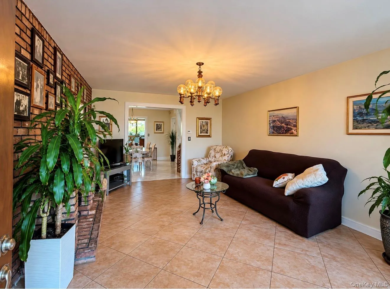Tiled flooring throughout, brick accent wall, and a multi-bulb chandelier Tiled flooring throughout, brick accent wall, and a multi-bulb chandelier