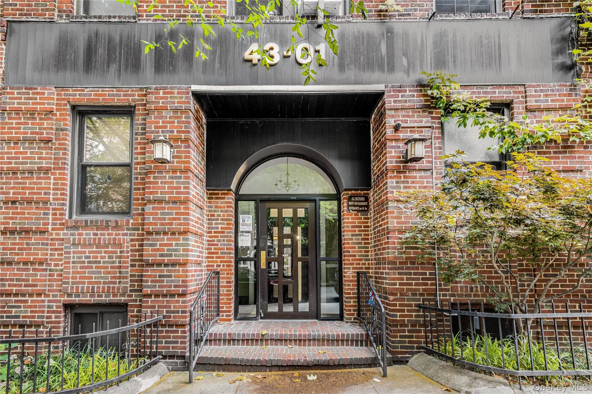 Brick exterior featuring an arched entryway, transom window, metal railings, and dual exterior sconces Brick exterior featuring an arched entryway, transom window, metal railings, and dual exterior sconces