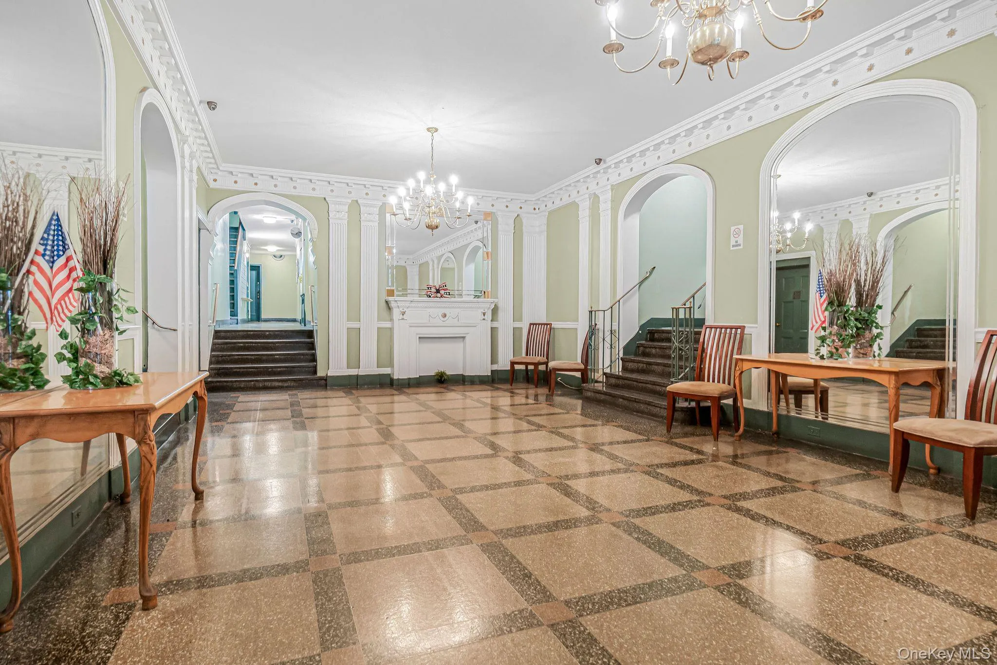 Patterned tile flooring, decorative wall molding, arched mirrors, a built-in fireplace mantel, and dual chandeliers Patterned tile flooring, decorative wall molding, arched mirrors, a built-in fireplace mantel, and dual chandeliers