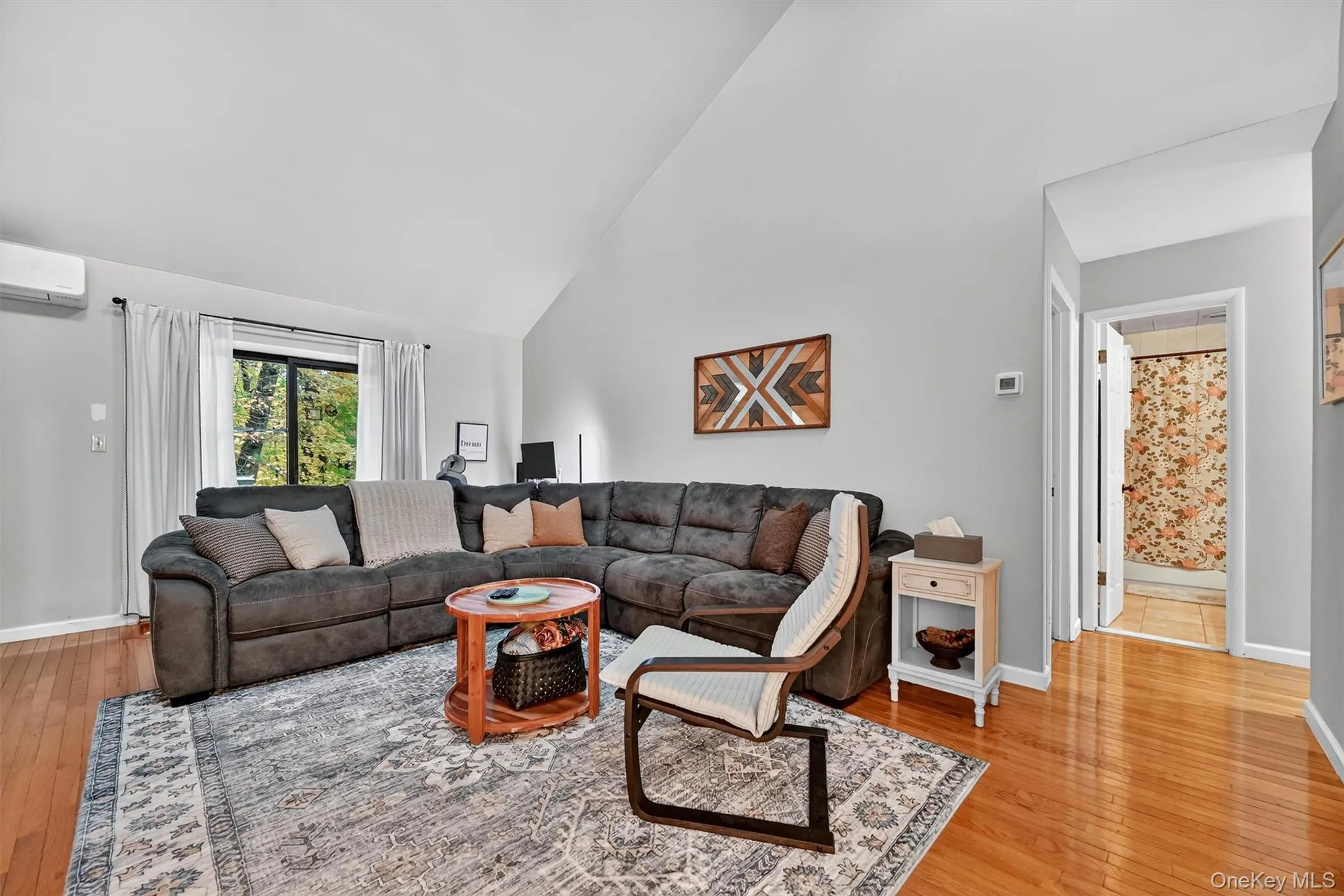 Living room featuring high vaulted ceiling, light wood finished floors, and a wall mounted AC Living room featuring high vaulted ceiling, light wood finished floors, and a wall mounted AC