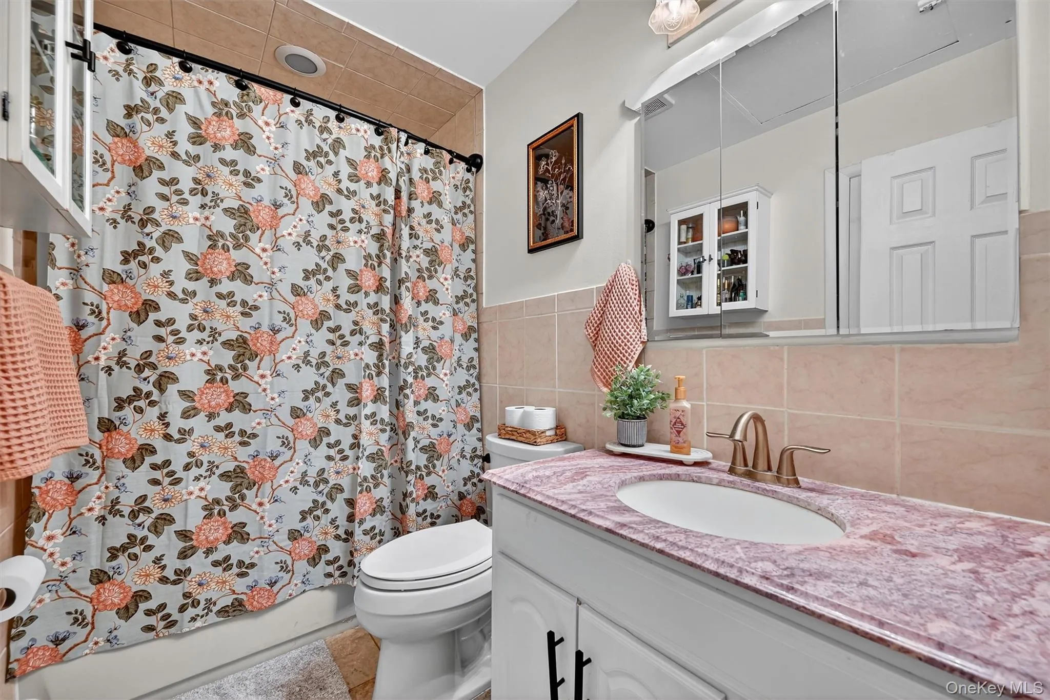 Full bath featuring tile walls, vanity, tile patterned floors, and shower / bathtub combination with curtain Full bath featuring tile walls, vanity, tile patterned floors, and shower / bathtub combination with curtain