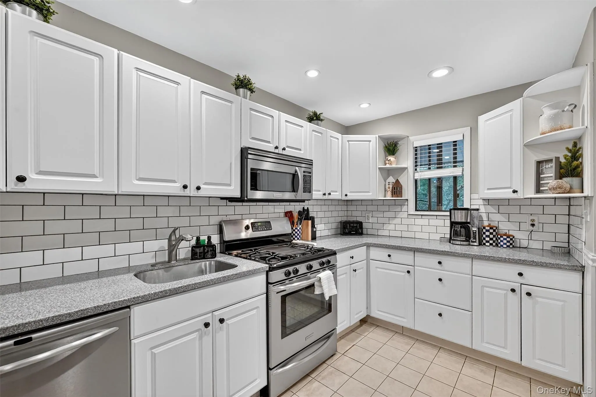 Kitchen with open shelves, stainless steel appliances, white cabinets, light stone countertops, and recessed lighting Kitchen with open shelves, stainless steel appliances, white cabinets, light stone countertops, and recessed lighting