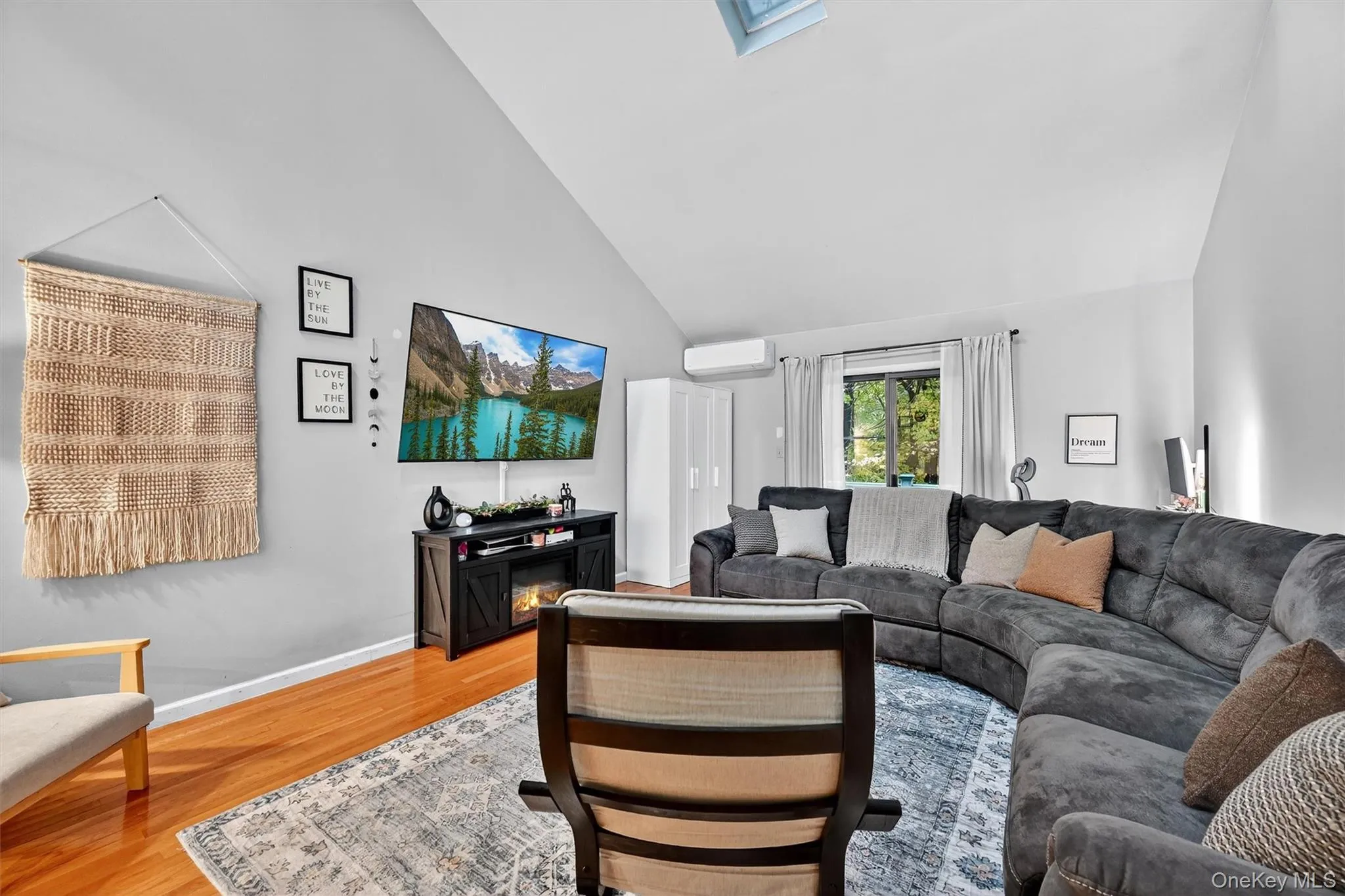 Living room with a skylight, high vaulted ceiling, and light wood finished floors Living room with a skylight, high vaulted ceiling, and light wood finished floors
