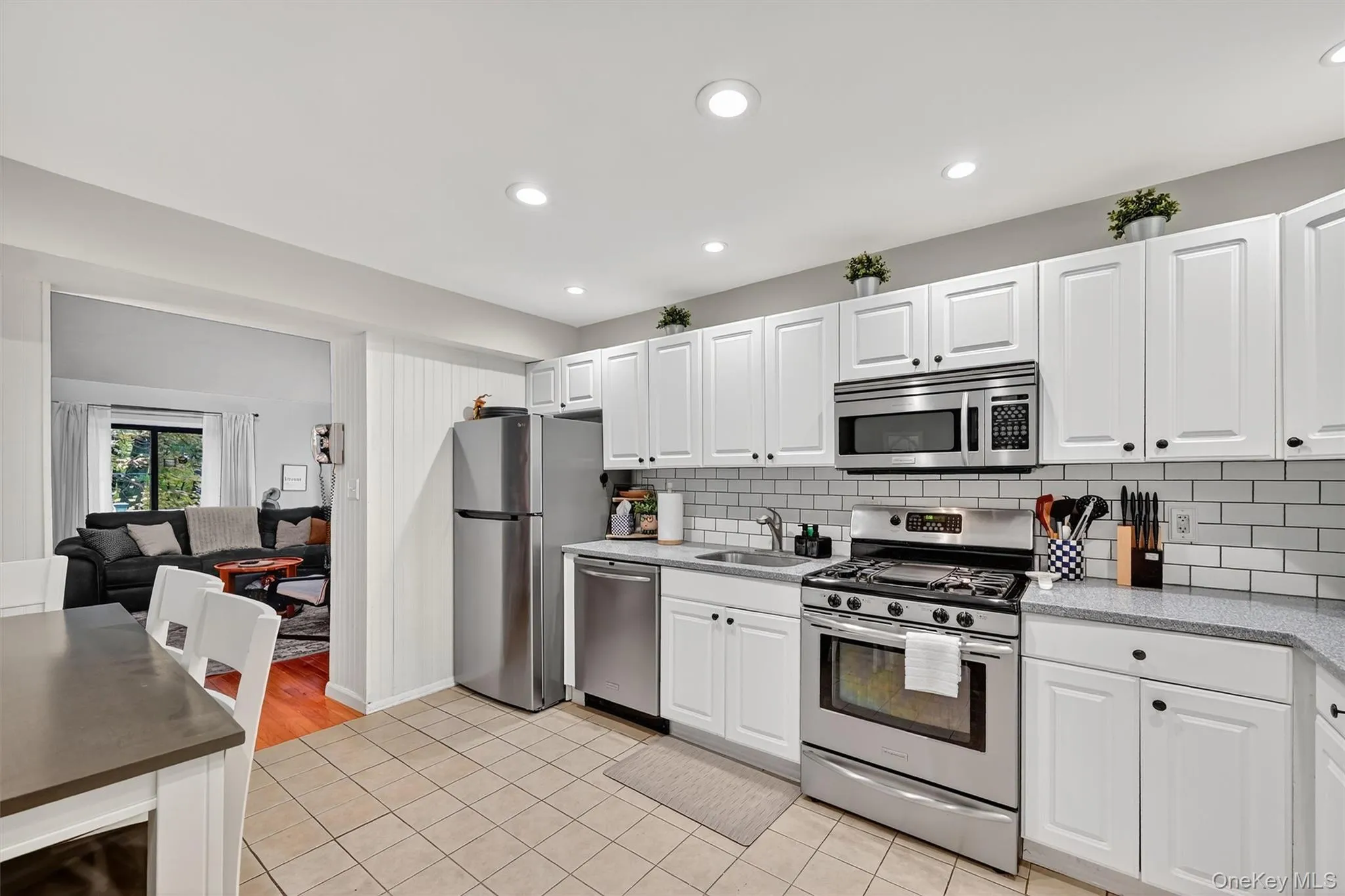 Kitchen featuring stainless steel appliances, white cabinetry, light tile patterned floors, tasteful backsplash, and recessed lighting Kitchen featuring stainless steel appliances, white cabinetry, light tile patterned floors, tasteful backsplash, and recessed lighting