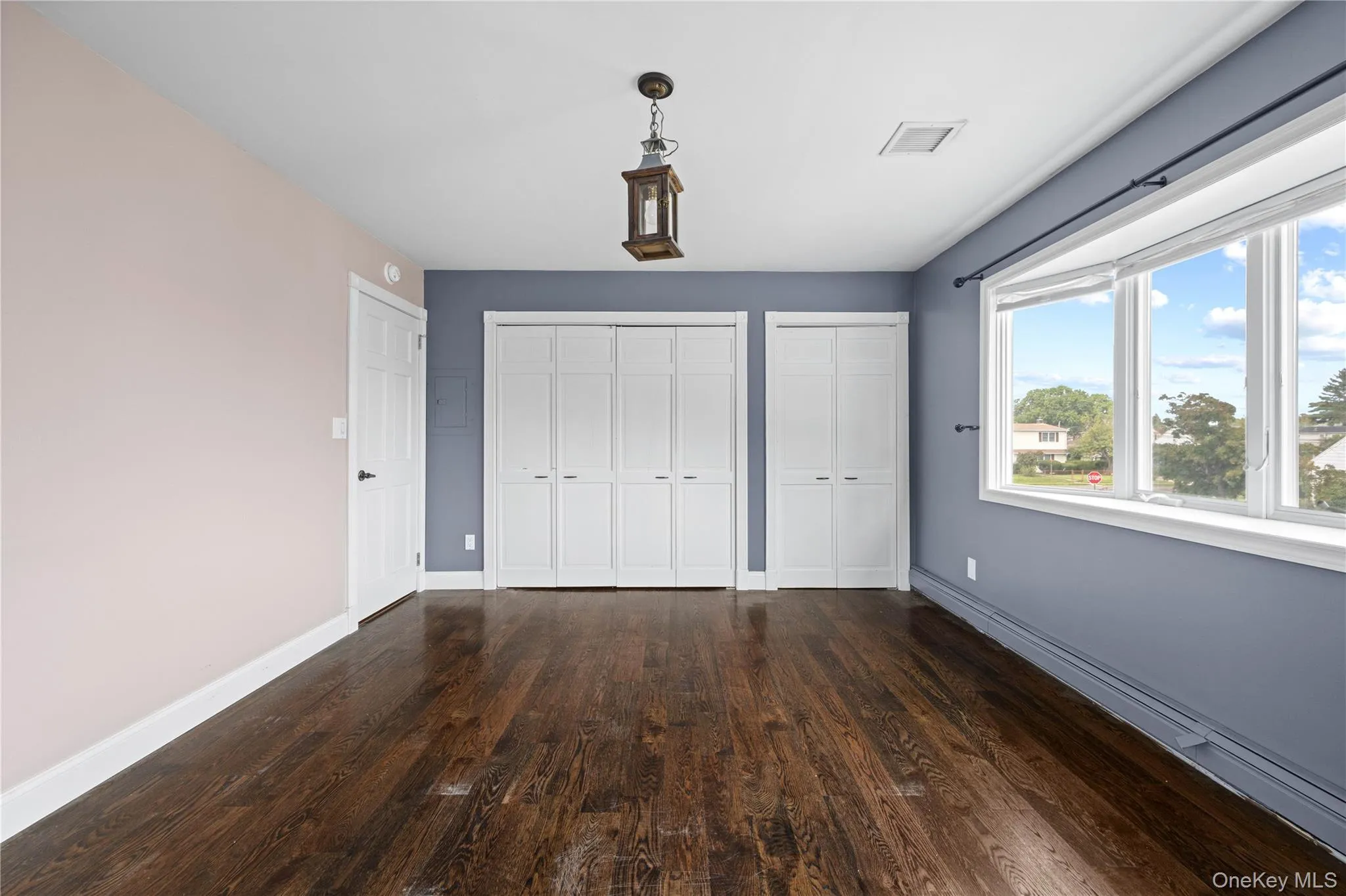 Dark wood-finish flooring, a decorative ceiling light fixture, and a bay window Dark wood-finish flooring, a decorative ceiling light fixture, and a bay window