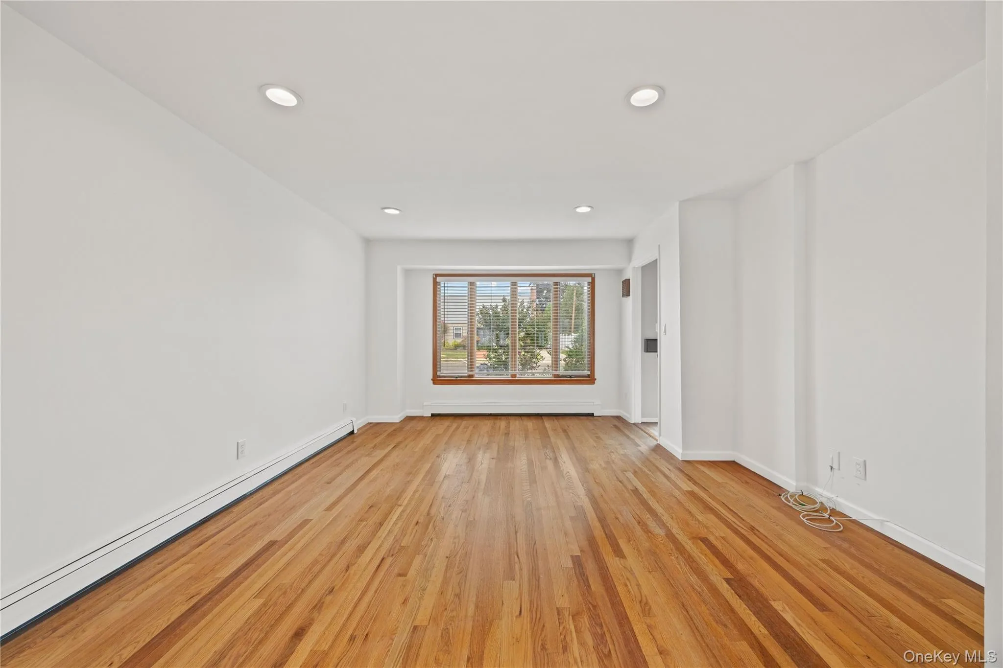Hardwood flooring, recessed ceiling lighting, and large picture windows with wood trim Hardwood flooring, recessed ceiling lighting, and large picture windows with wood trim
