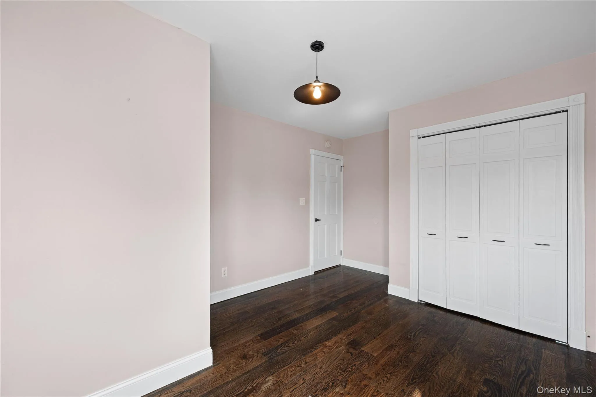 Dark wood-finish flooring, light-toned wall paint, crisp white trim, and a contemporary ceiling fixture Dark wood-finish flooring, light-toned wall paint, crisp white trim, and a contemporary ceiling fixture