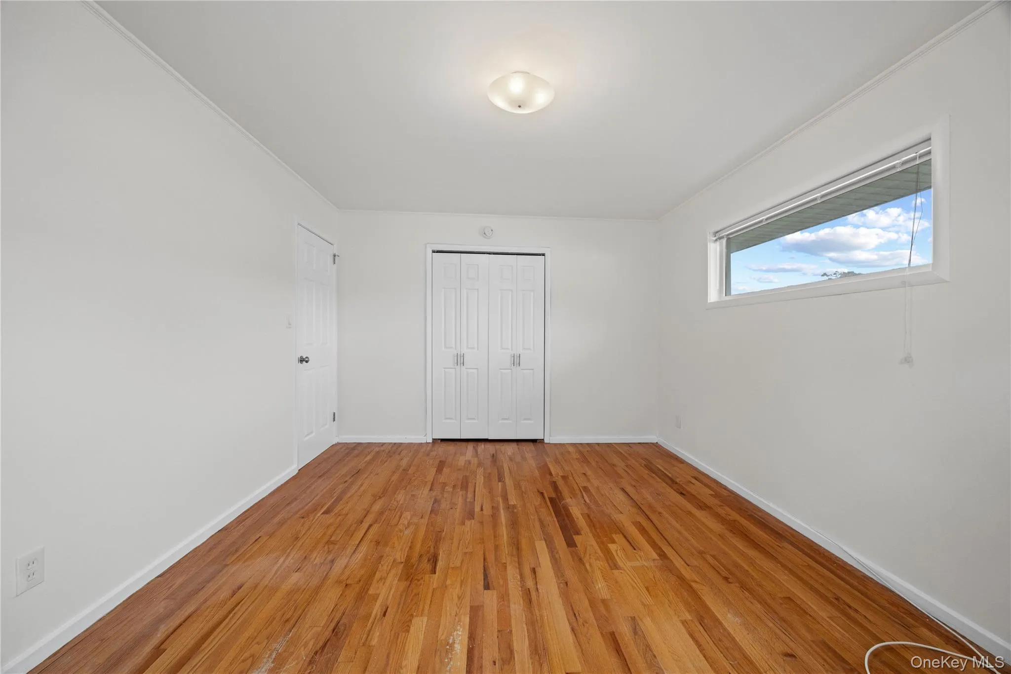 Hardwood flooring, white walls, flush mount ceiling light, horizontal window with roller shade, bi-fold closet doors Hardwood flooring, white walls, flush mount ceiling light, horizontal window with roller shade, bi-fold closet doors